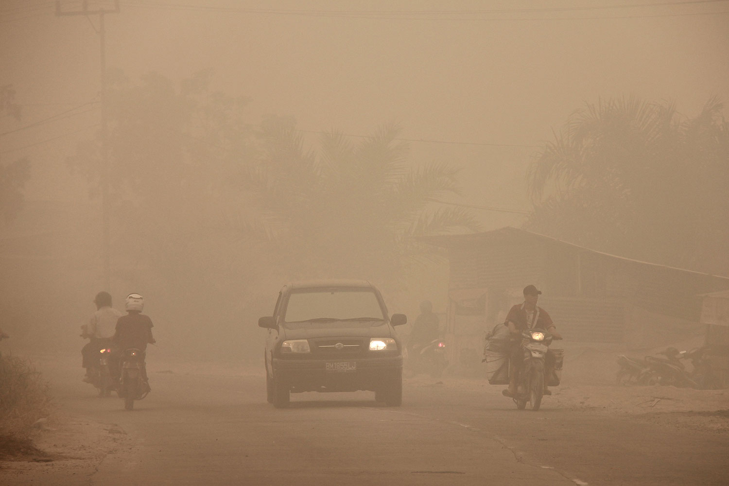 Indonesian motorists travel under a blanket of haze in Dumai town located in Riau province in Indonesia's Sumatra island on March 3, 2014. Riau province, the heart of a Southeast Asian smog crisis last year, has declared a state of emergency after being blanketed in thick haze from forest fires