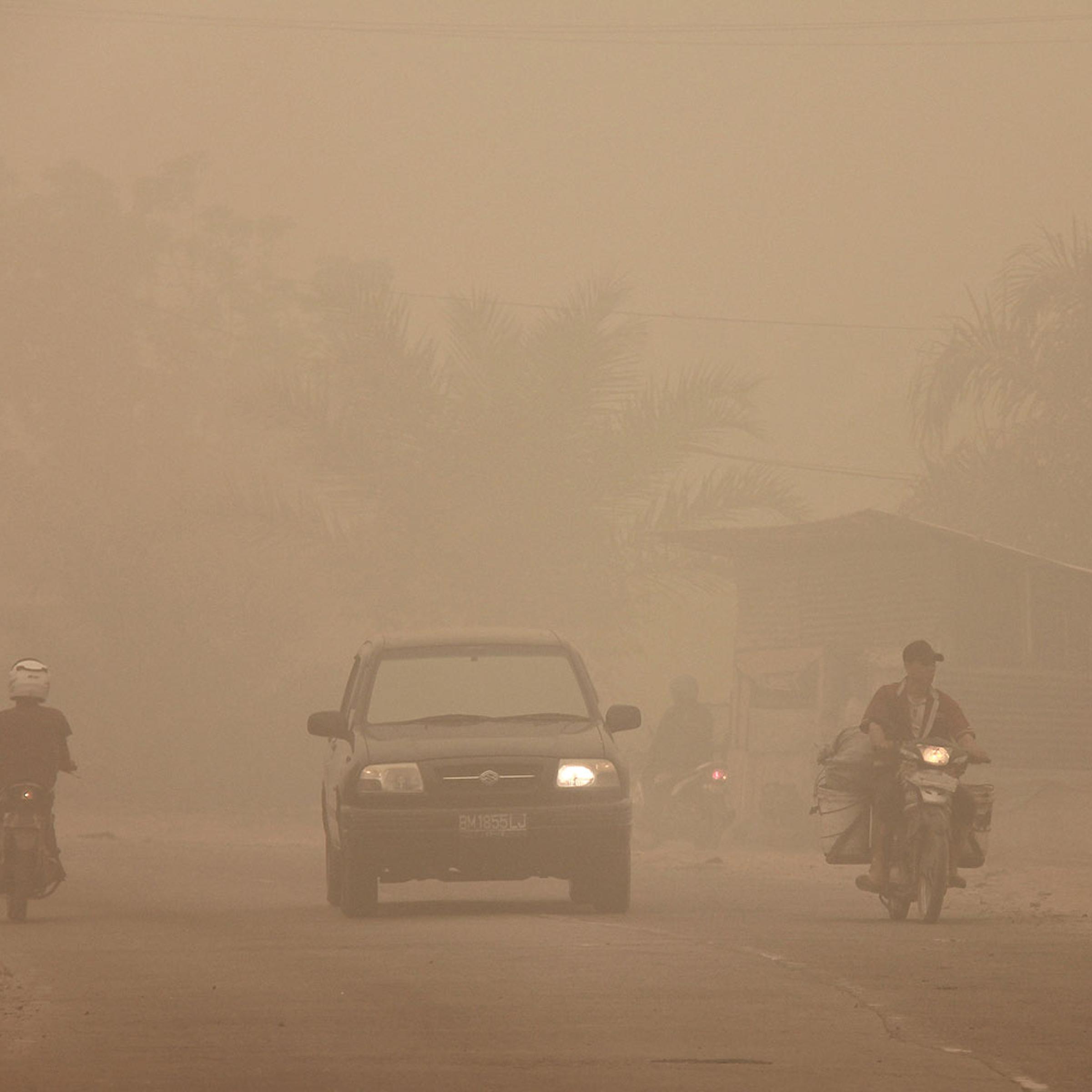 Indonesian motorists travel under a blanket of haze in Dumai town located in Riau province in Indonesia's Sumatra island on March 3, 2014. Riau province, the heart of a Southeast Asian smog crisis last year, has declared a state of emergency after being blanketed in thick haze from forest fires