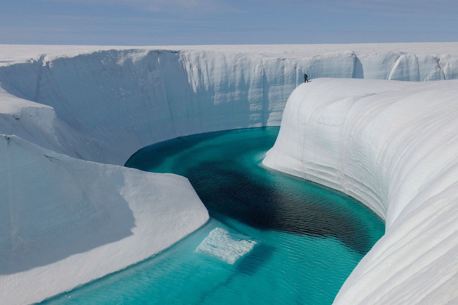 Extreme Ice Survey field assistant Adam LeWinter on the northeast rim of Birthday Canyon, atop feature called "Moab." Greenland Ice Sheet, July 2009.<br><br>Black deposit in bottom of channel is cryoconite. Birthday Canyon is approximately 150 feet deep.