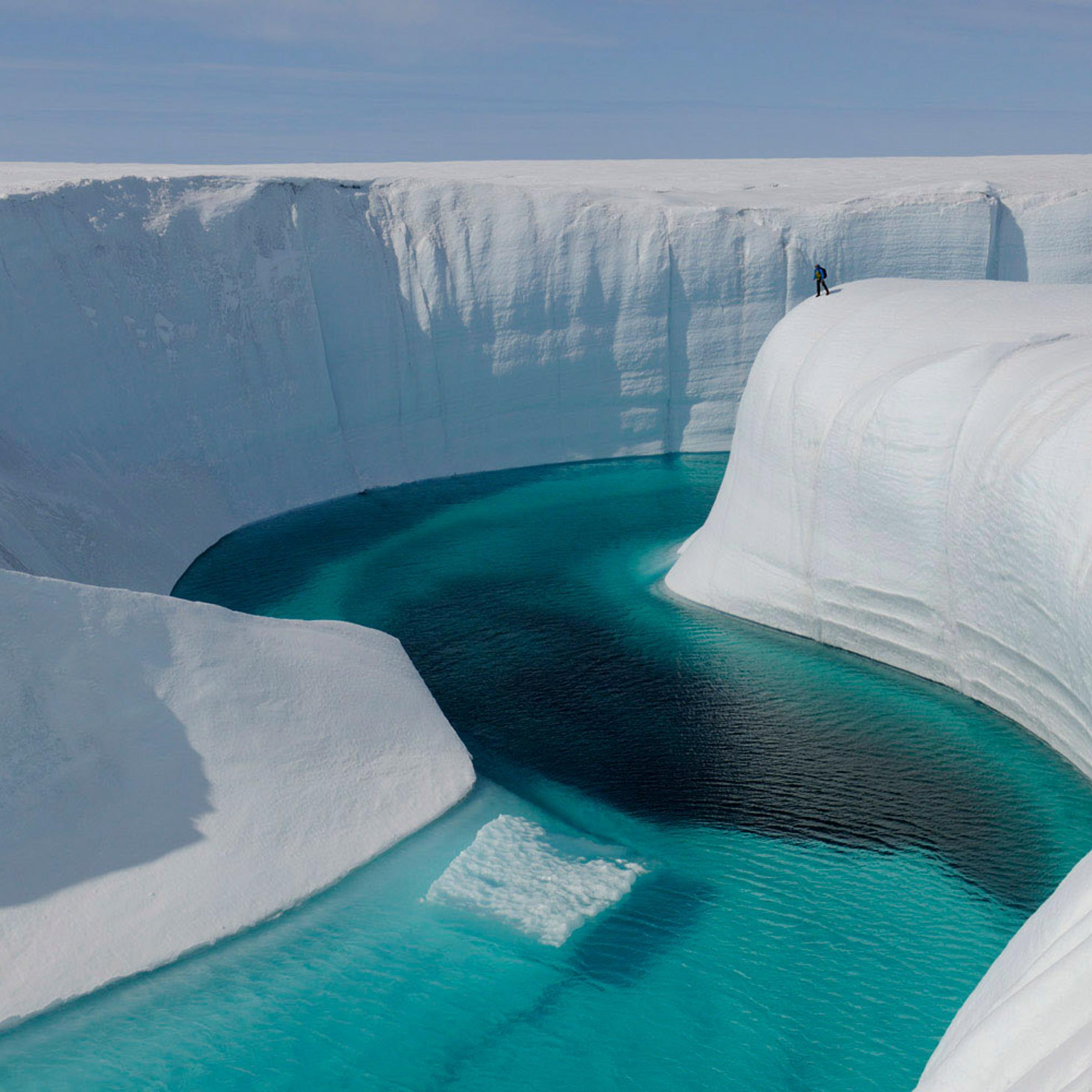 Extreme Ice Survey field assistant Adam LeWinter on the northeast rim of Birthday Canyon, atop feature called "Moab." Greenland Ice Sheet, July 2009.<br><br>Black deposit in bottom of channel is cryoconite. Birthday Canyon is approximately 150 feet deep.