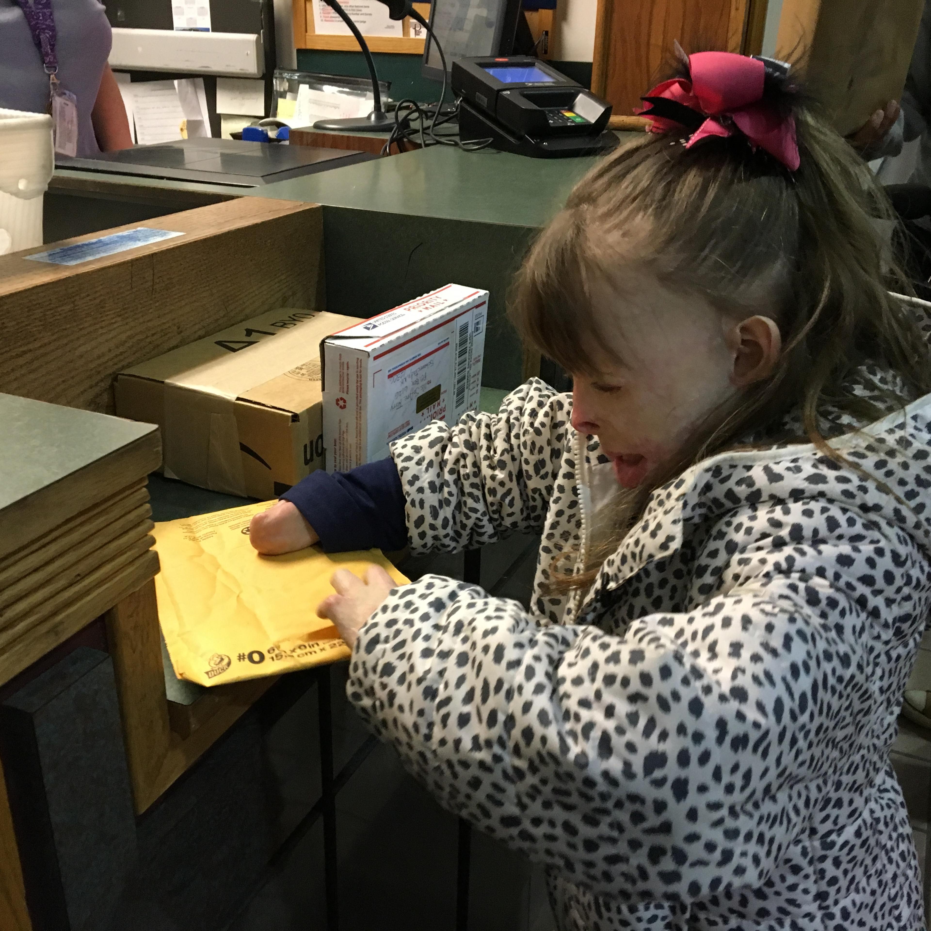 Safyre Terry opens a gift at a post office near her home in Rotterdam, NY.