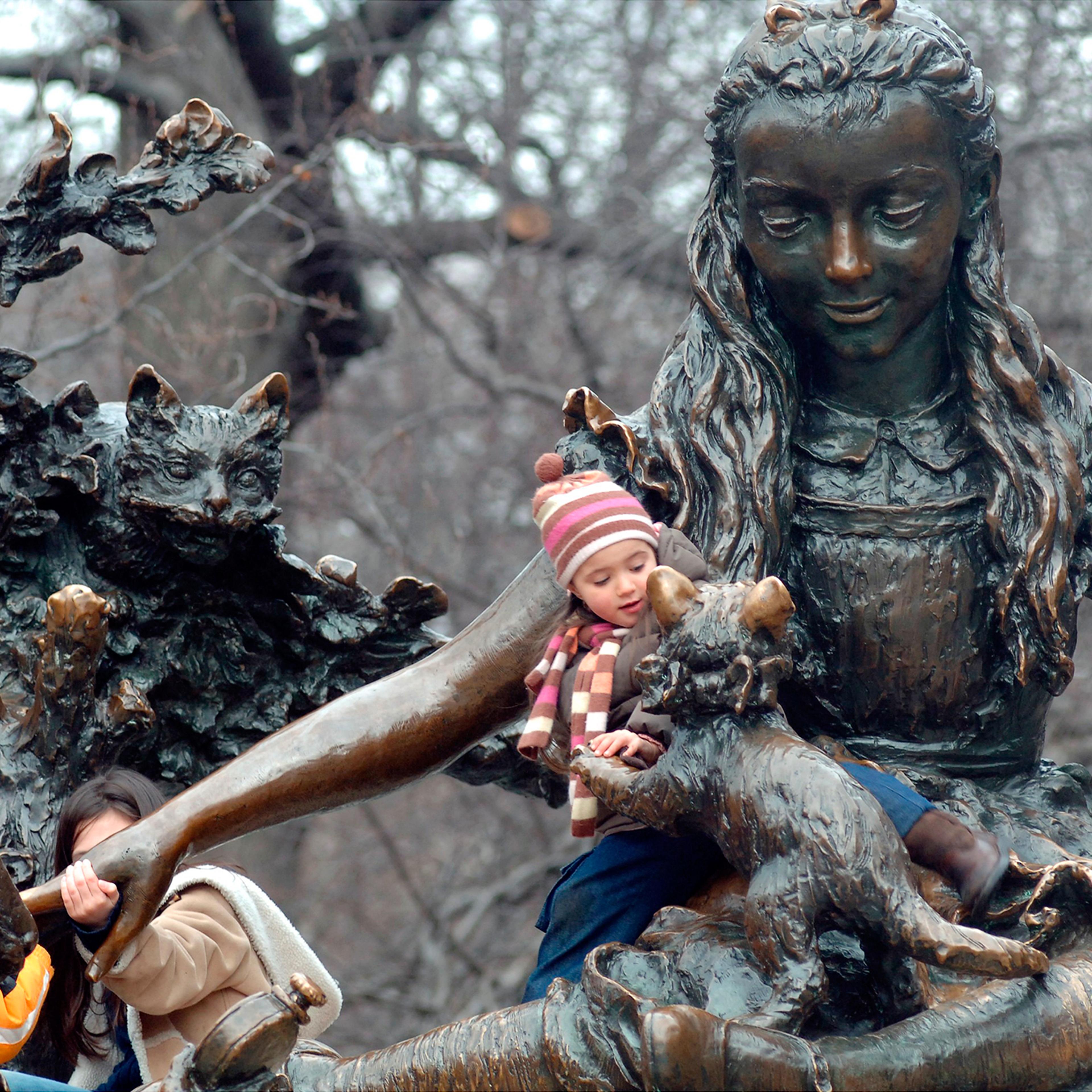 Children play on Central Park’s Alice in Wonderland, one of three monuments to notable women