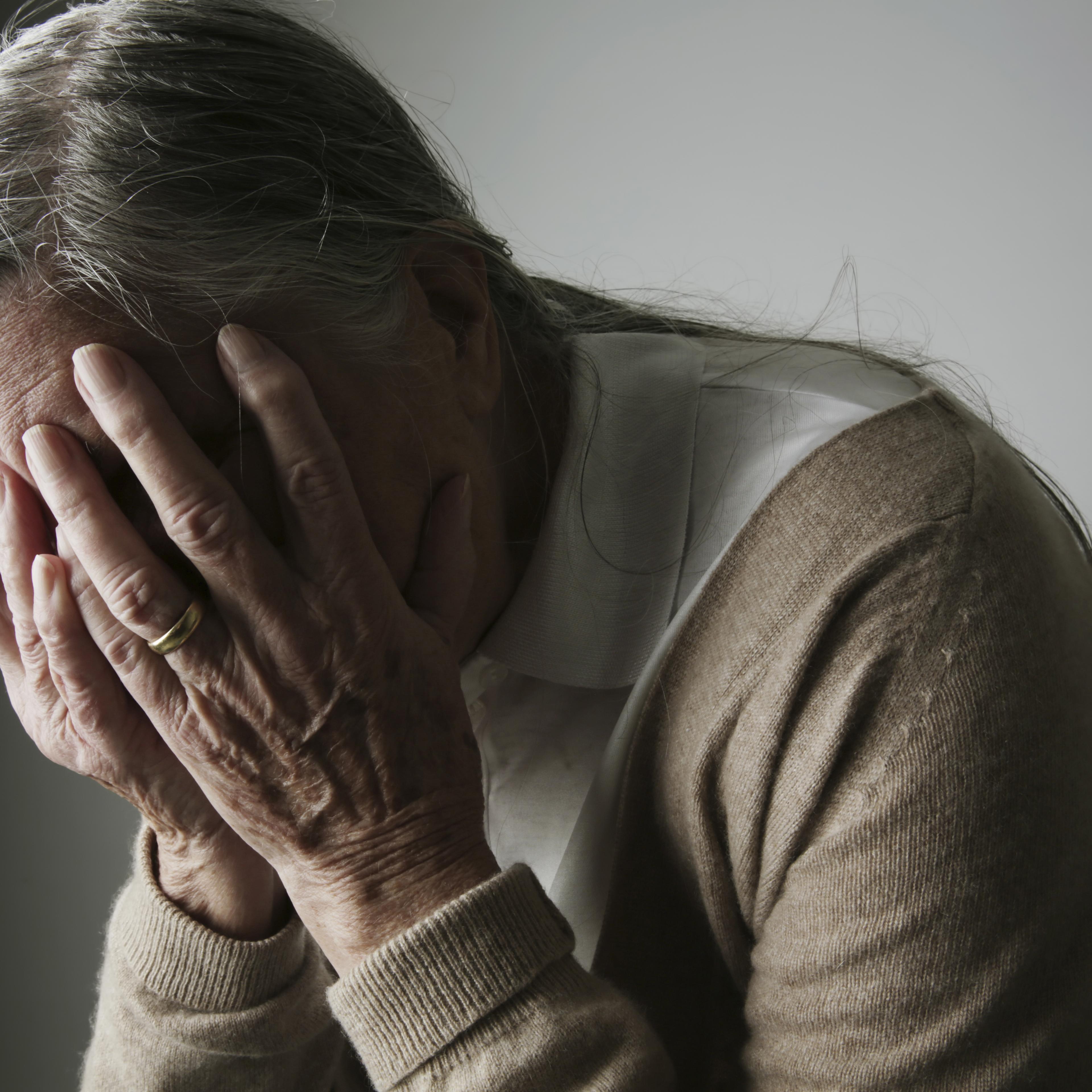 Senior woman covering face with her hands