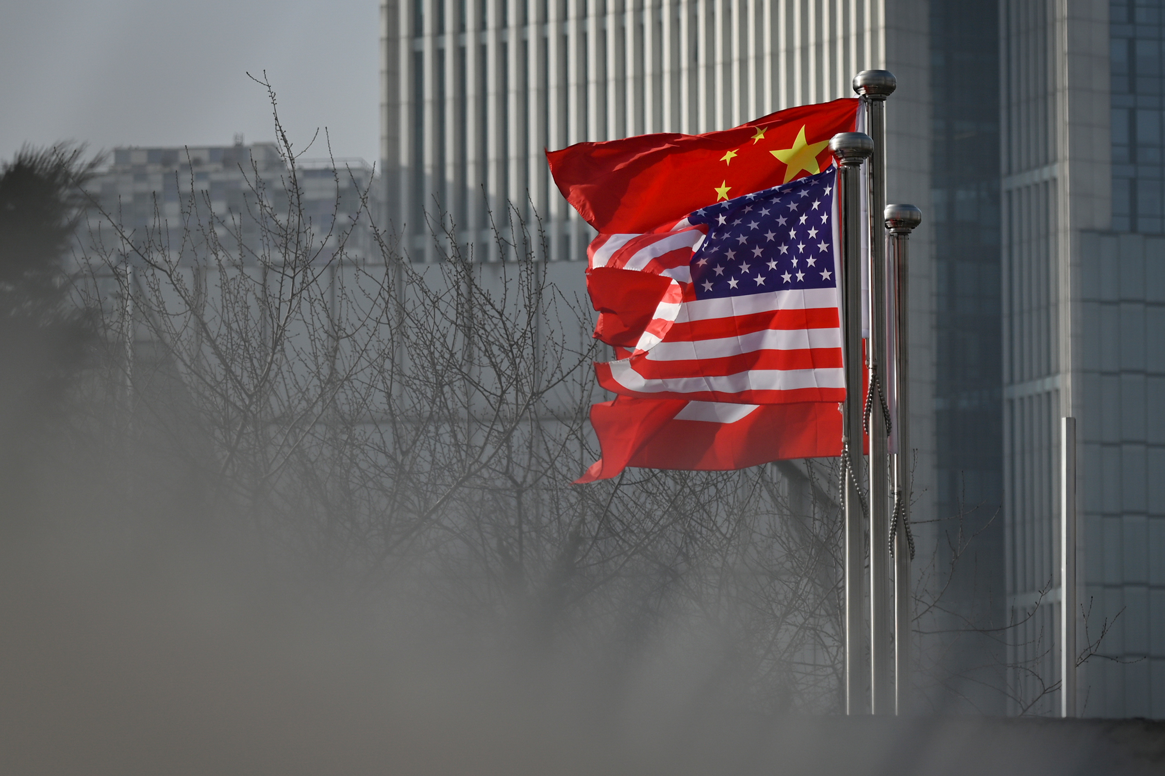 Chinese and U.S. national flags flutter at the entrance of an office building in Beijing on Jan. 19, 2020.