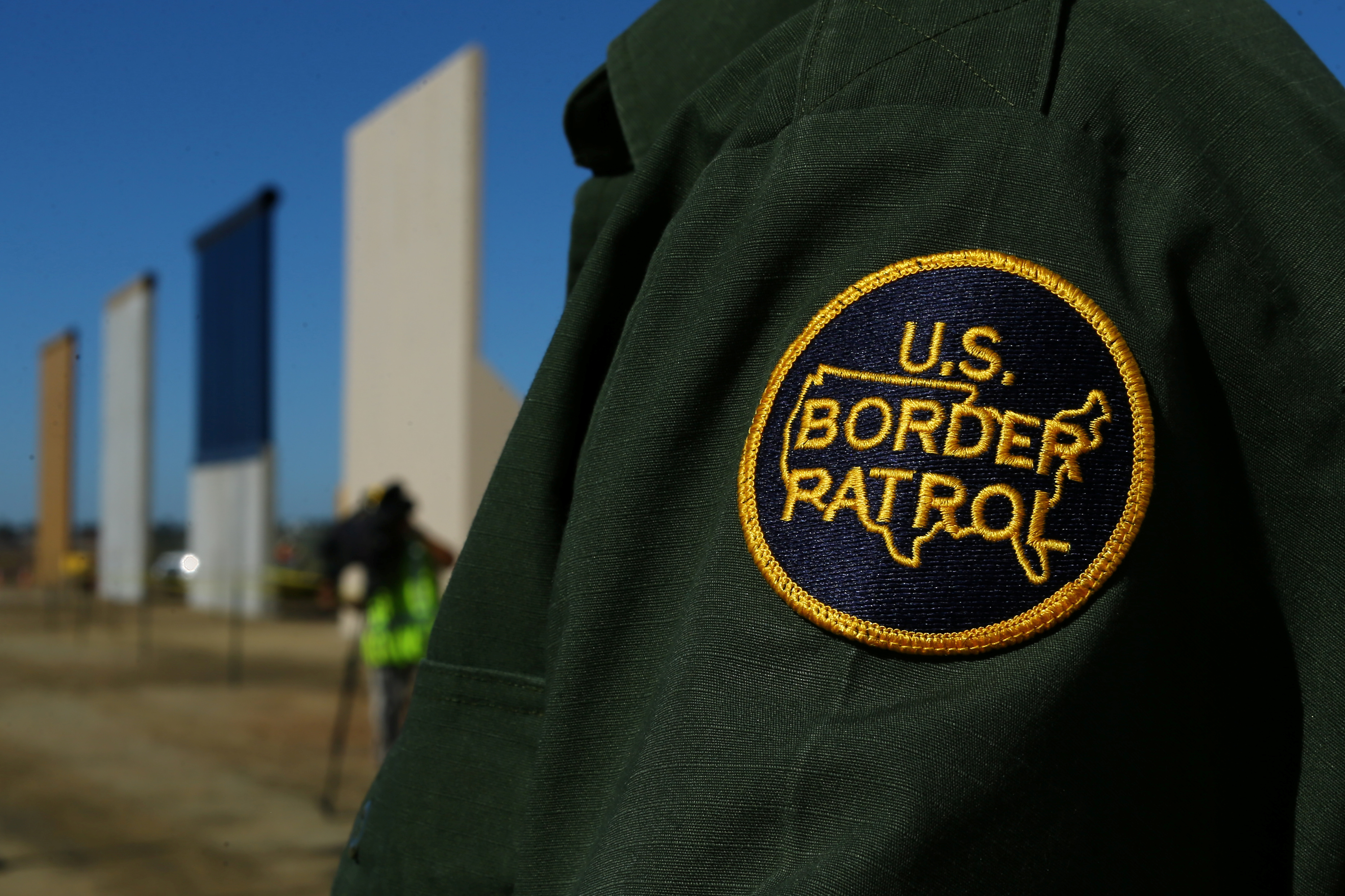 A border patrol officer stands next to some of U.S. President Donald Trump's eight border wall prototypes as they near completion along U.S.- Mexico border in San Diego