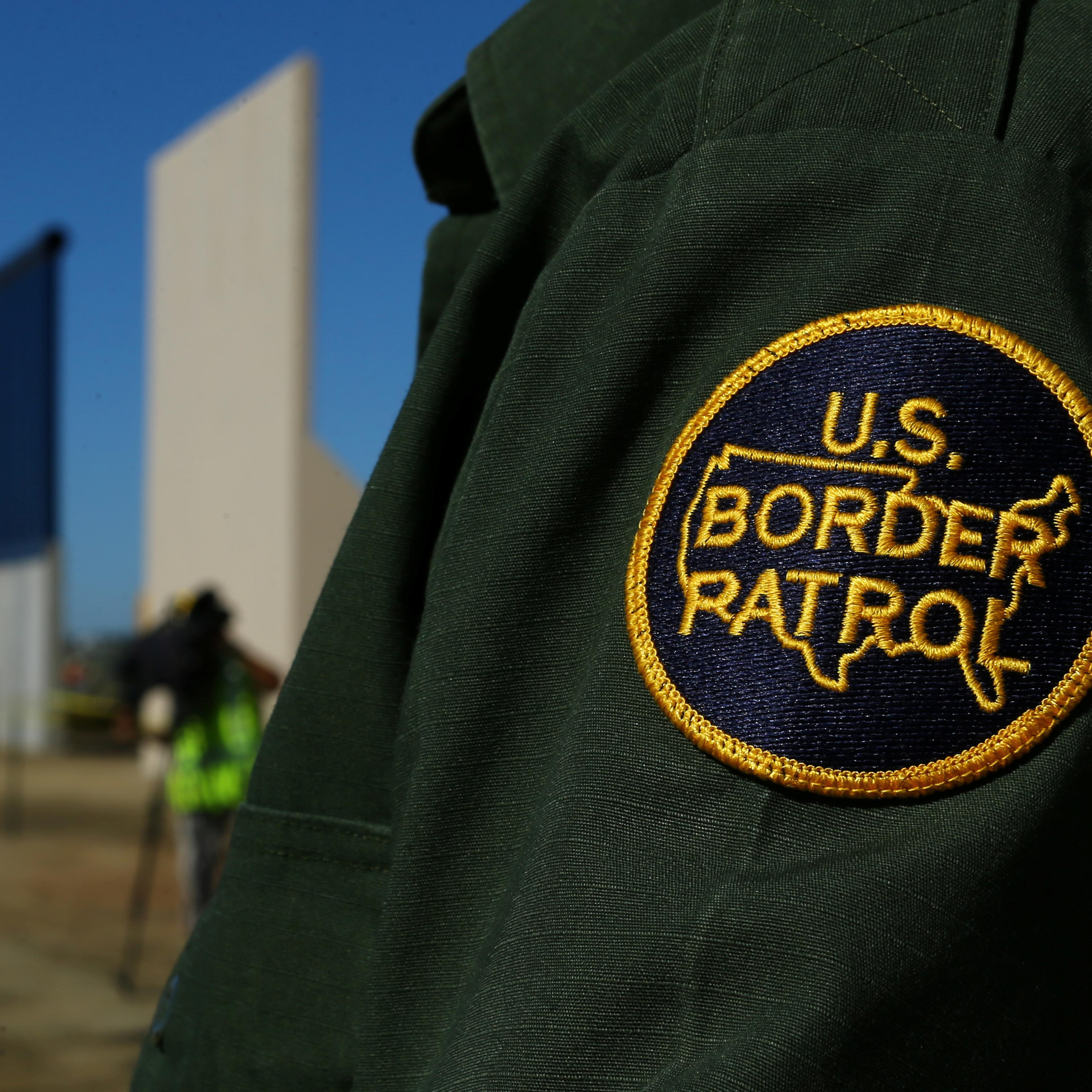 A border patrol officer stands next to some of U.S. President Donald Trump's eight border wall prototypes as they near completion along U.S.- Mexico border in San Diego