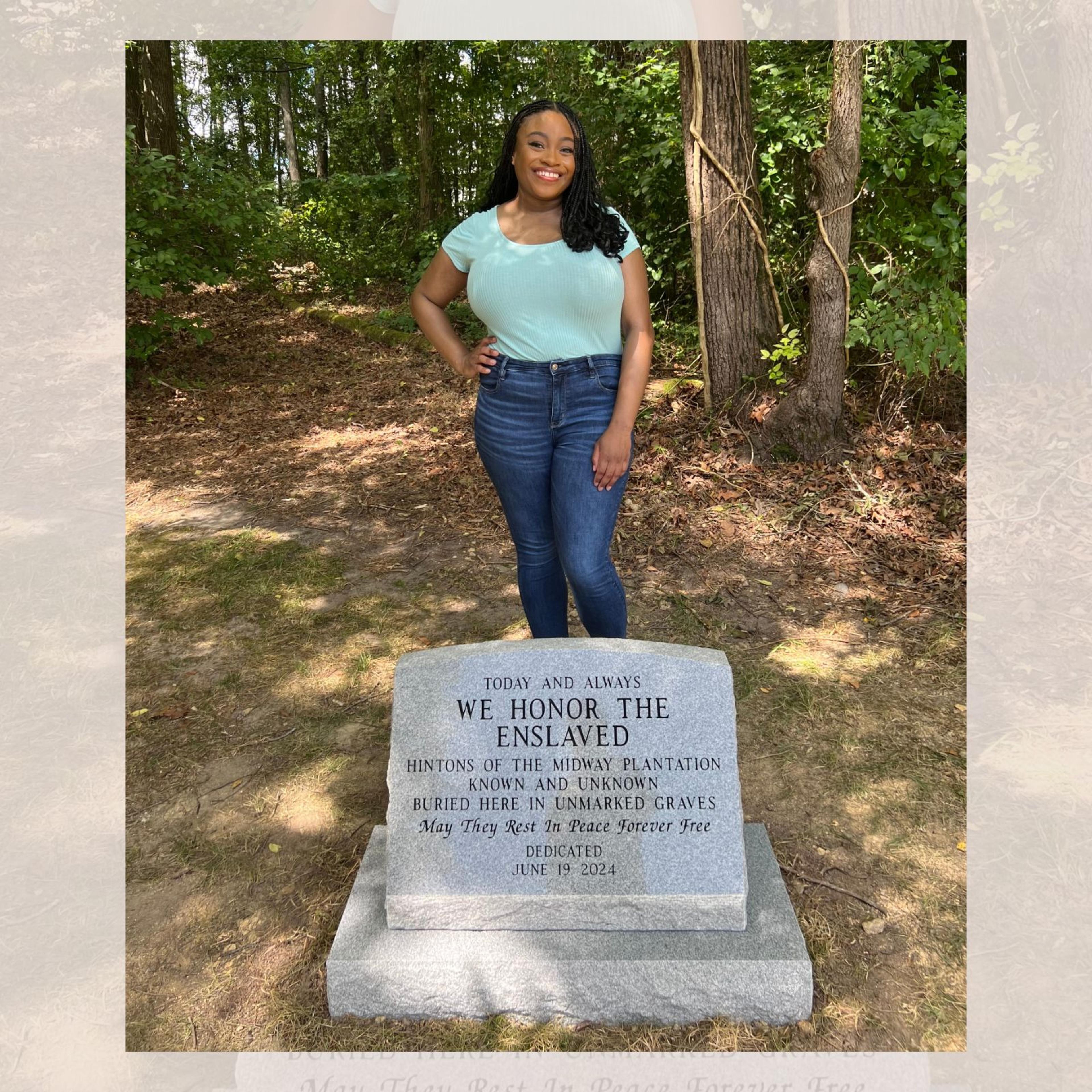 Author, Sade Green, pictured with burial site historical marker, which reads "Today and always, we honor the enslaved Hintons of the Midway Plantation, known and unknown, buried here in unmarked graves. May they rest in peace forever free. Dedicated June 19, 2024.”