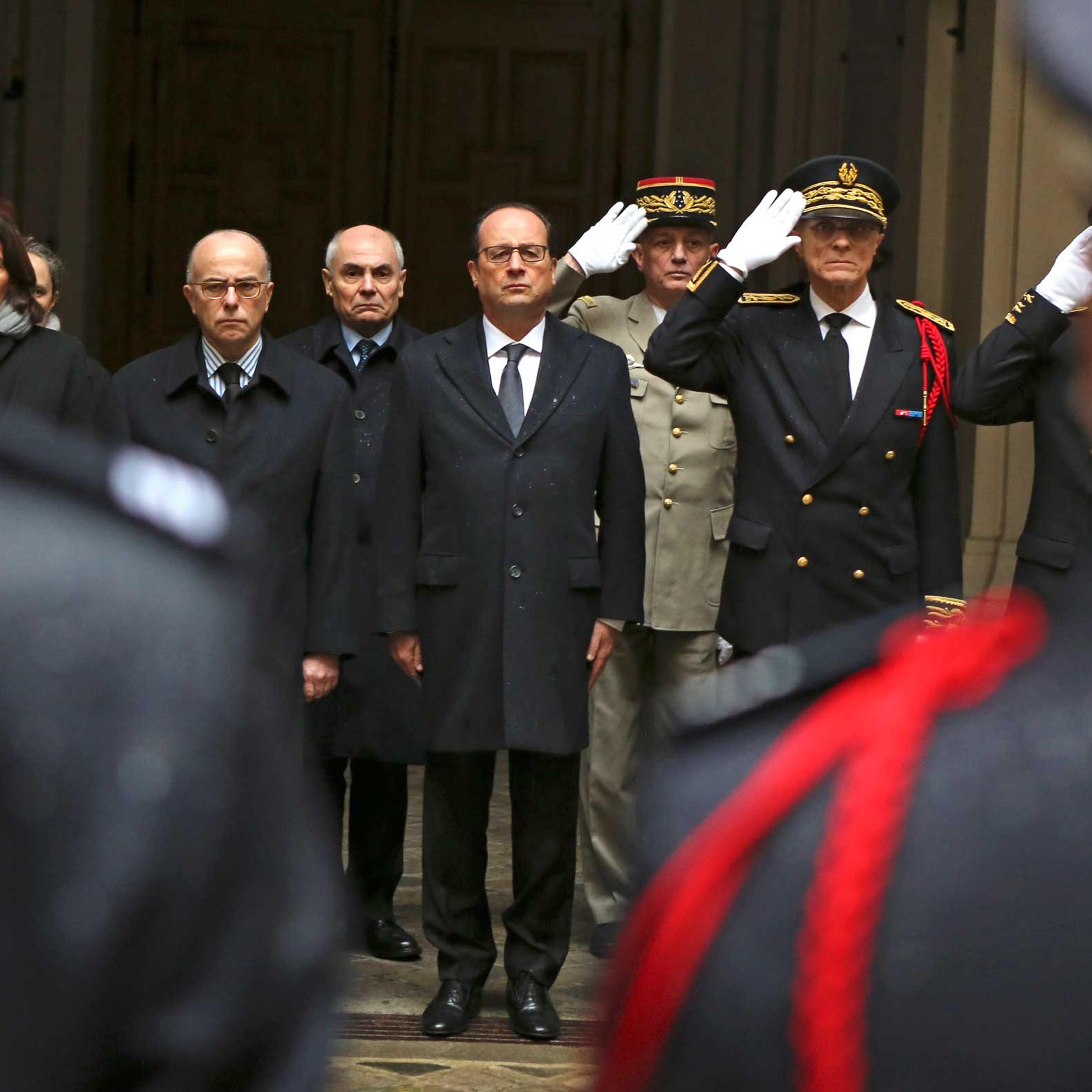 French President Francois Hollande, center, with at his side interior minister Bernard Cazeneuve, left, and Paris police prefect Bernard Boucault, right, stands for a minute of silence, at Paris Prefecture in Paris, Jan. 8, 2015.