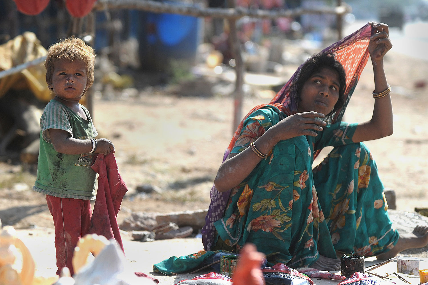 An Indian labourer sits with a child outside a makeshift shelter on a highway on the outskirts of Hyderabad on Nov. 14, 2013