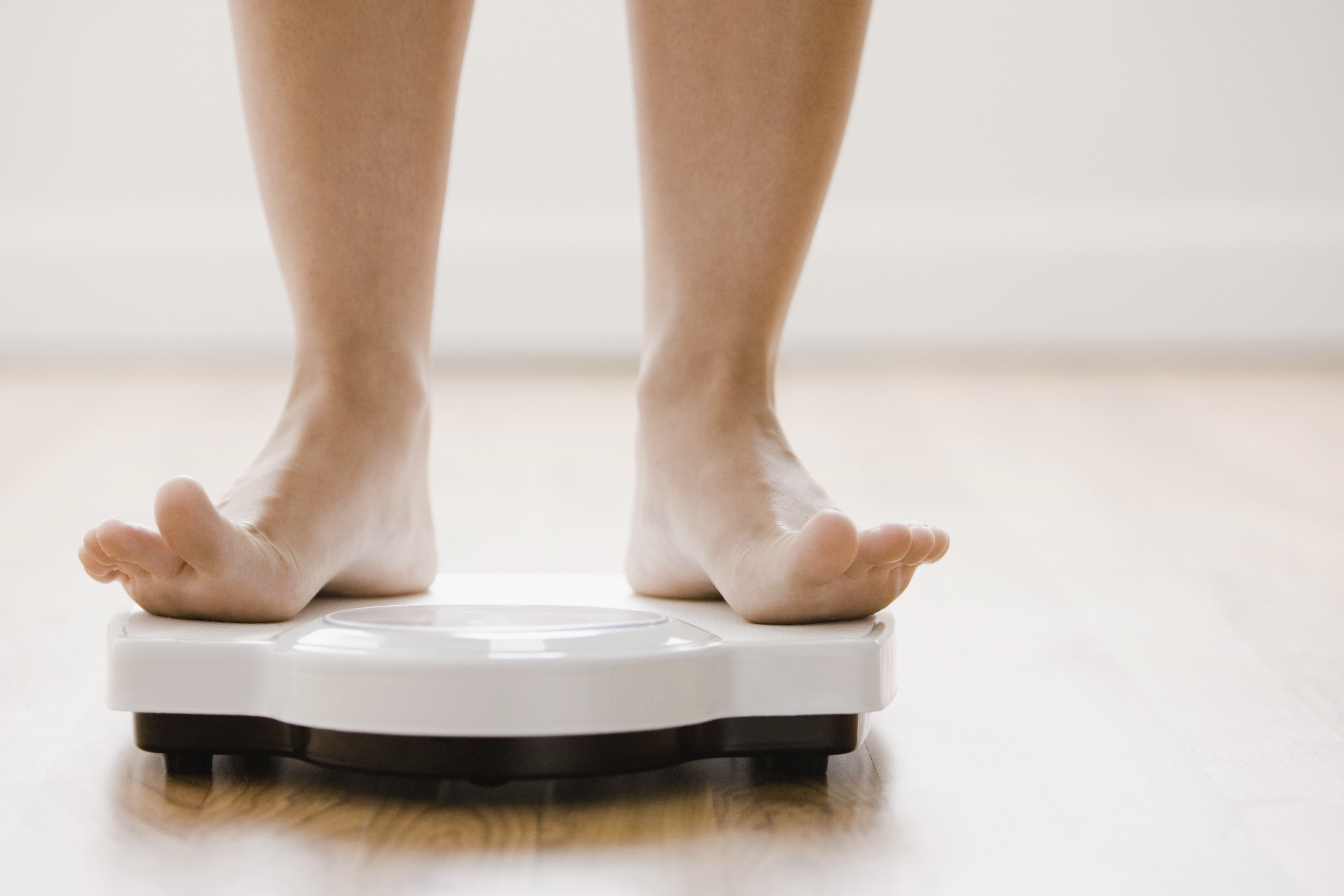 Caucasian woman's feet standing on scale TIME health stock