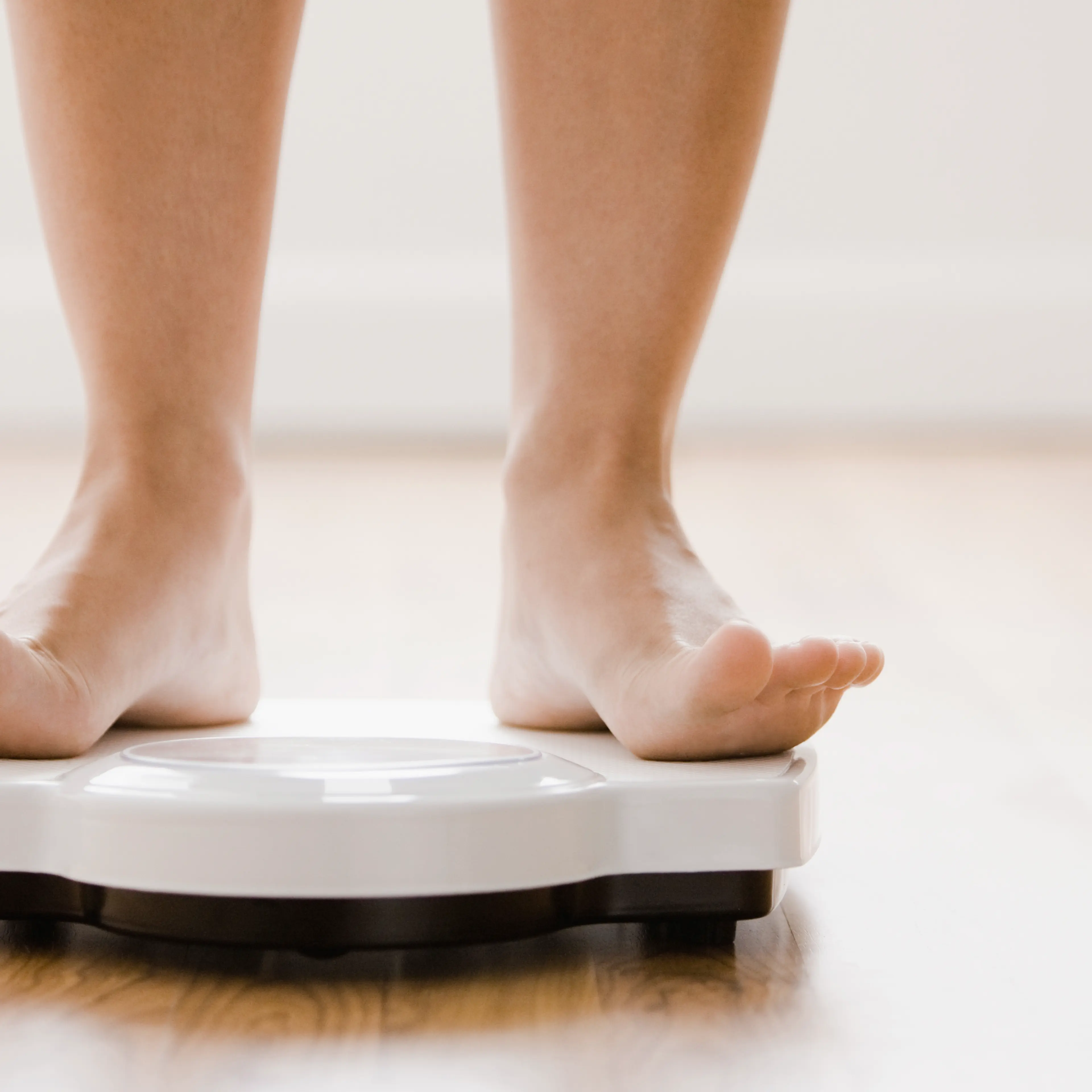 Caucasian woman's feet standing on scale TIME health stock