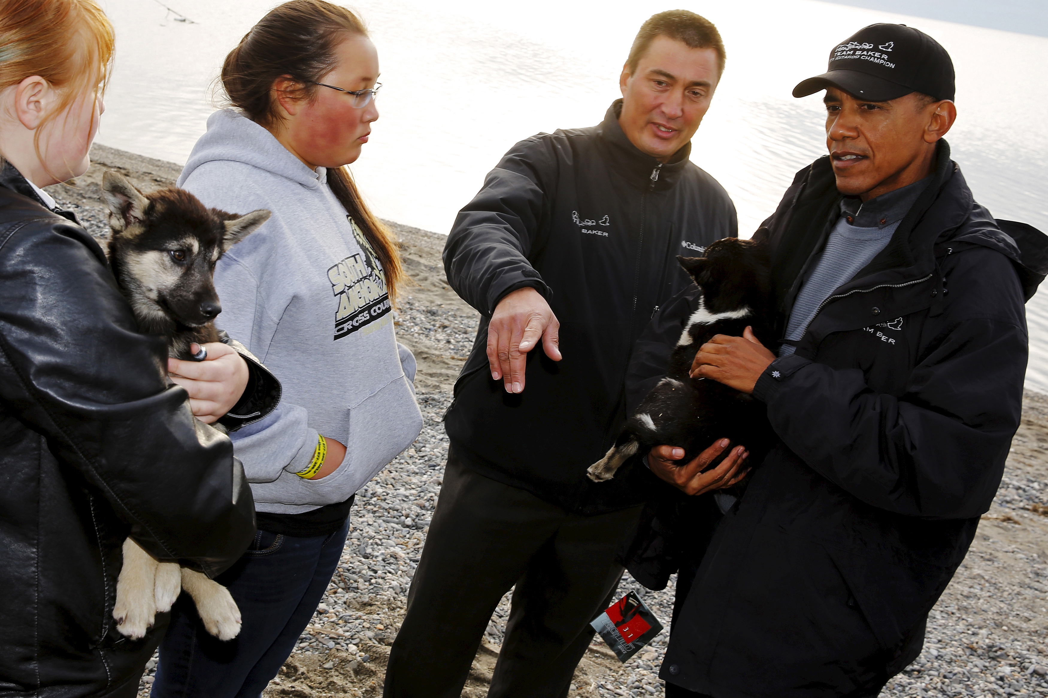 U.S. President Barack Obama (R) looks at dog sled puppies belonging to 2011 Iditarod Dog Sled Race champion John Baker in Kotzebue, Alaska on Sept. 2, 2015.