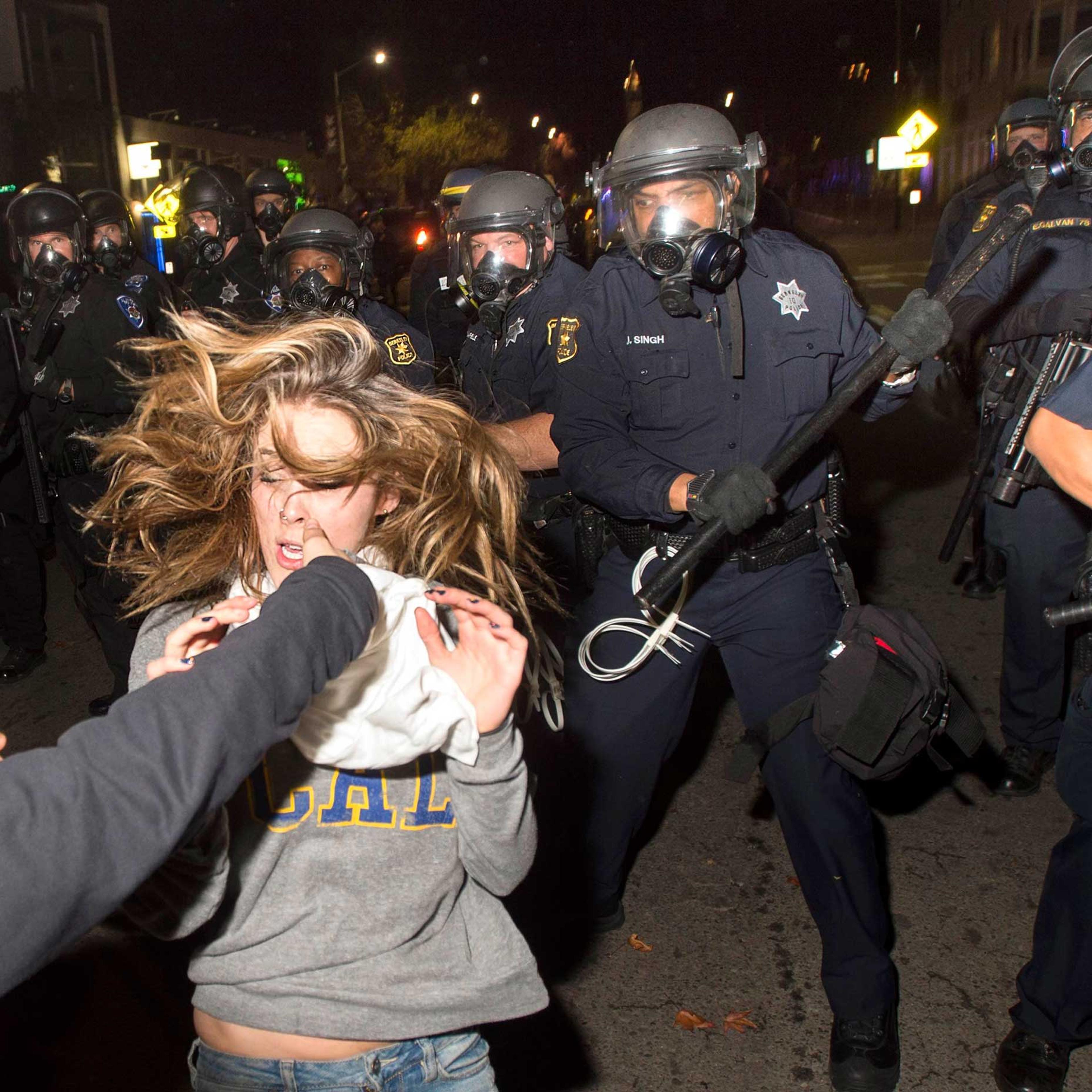 A protester flees as police officers try to disperse a crowd comprised largely of student demonstrators during a protest against police violence in the U.S., in Berkeley