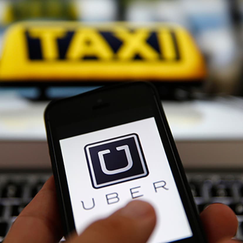 An illustration picture shows the logo of car-sharing service app Uber on a smartphone next to the picture of an official German taxi sign in Frankfurt, September 15, 2014.