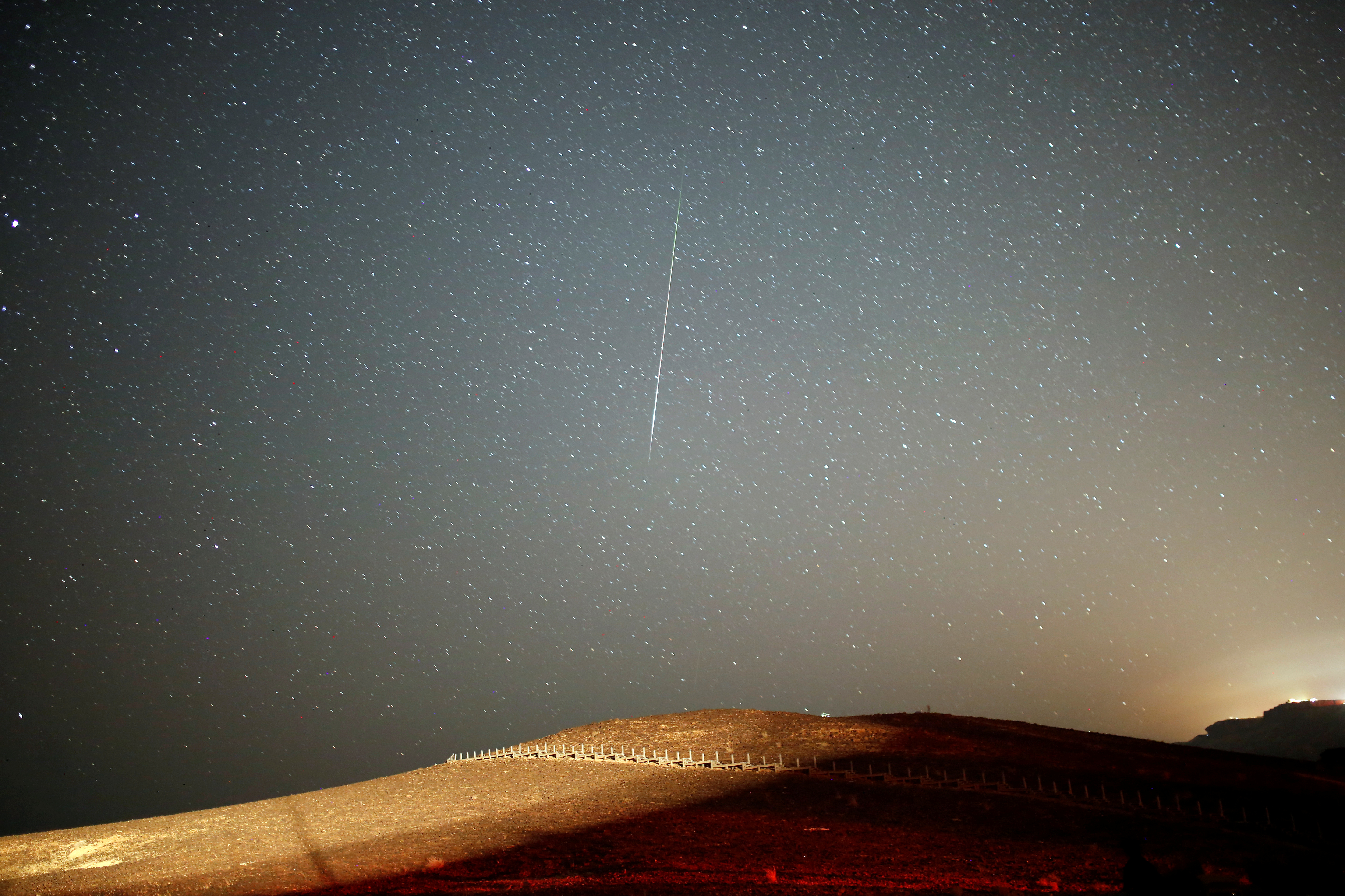 A meteor streaks across the sky in the early morning during the Perseid meteor shower in Ramon Crater near the town of Mitzpe Ramon