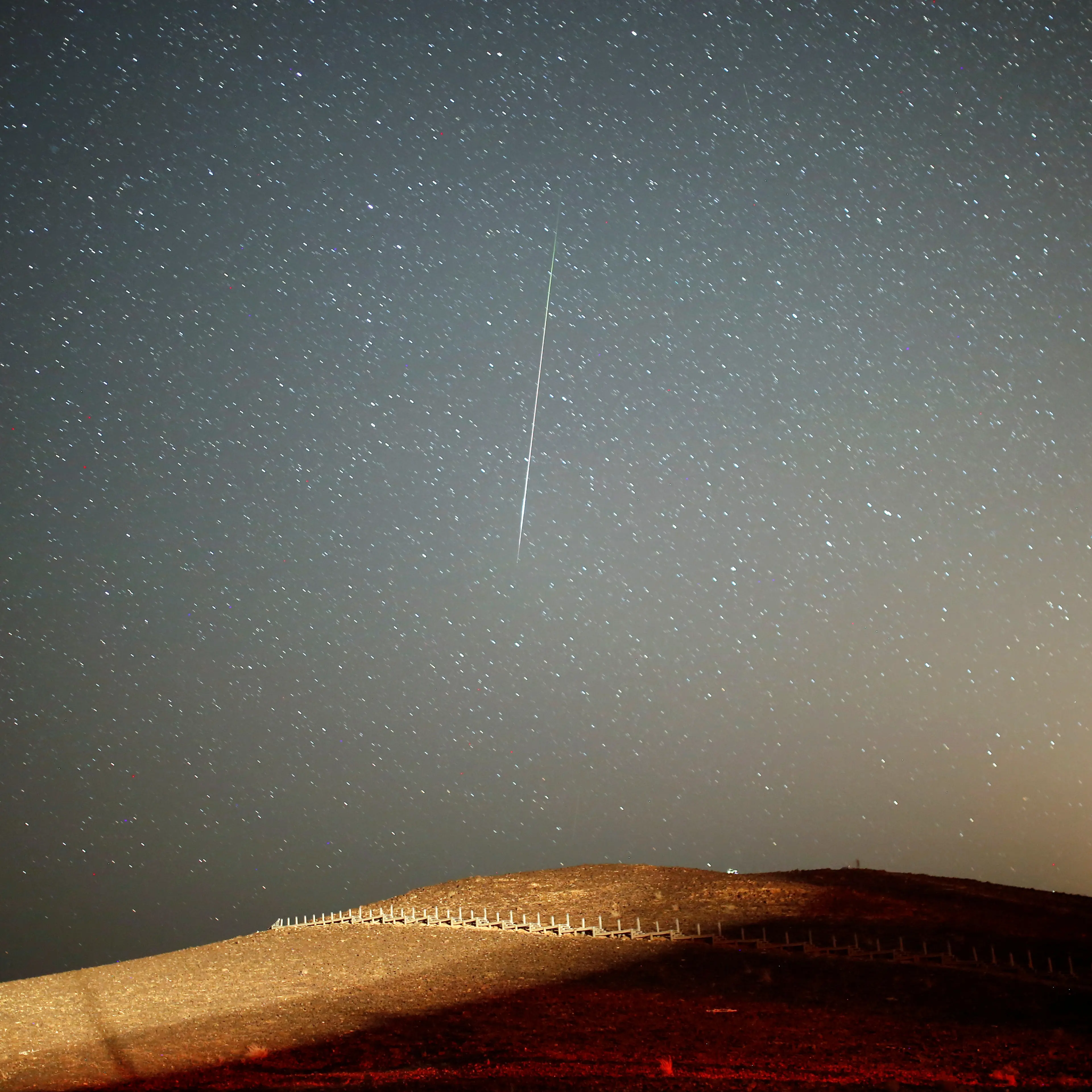 A meteor streaks across the sky in the early morning during the Perseid meteor shower in Ramon Crater near the town of Mitzpe Ramon