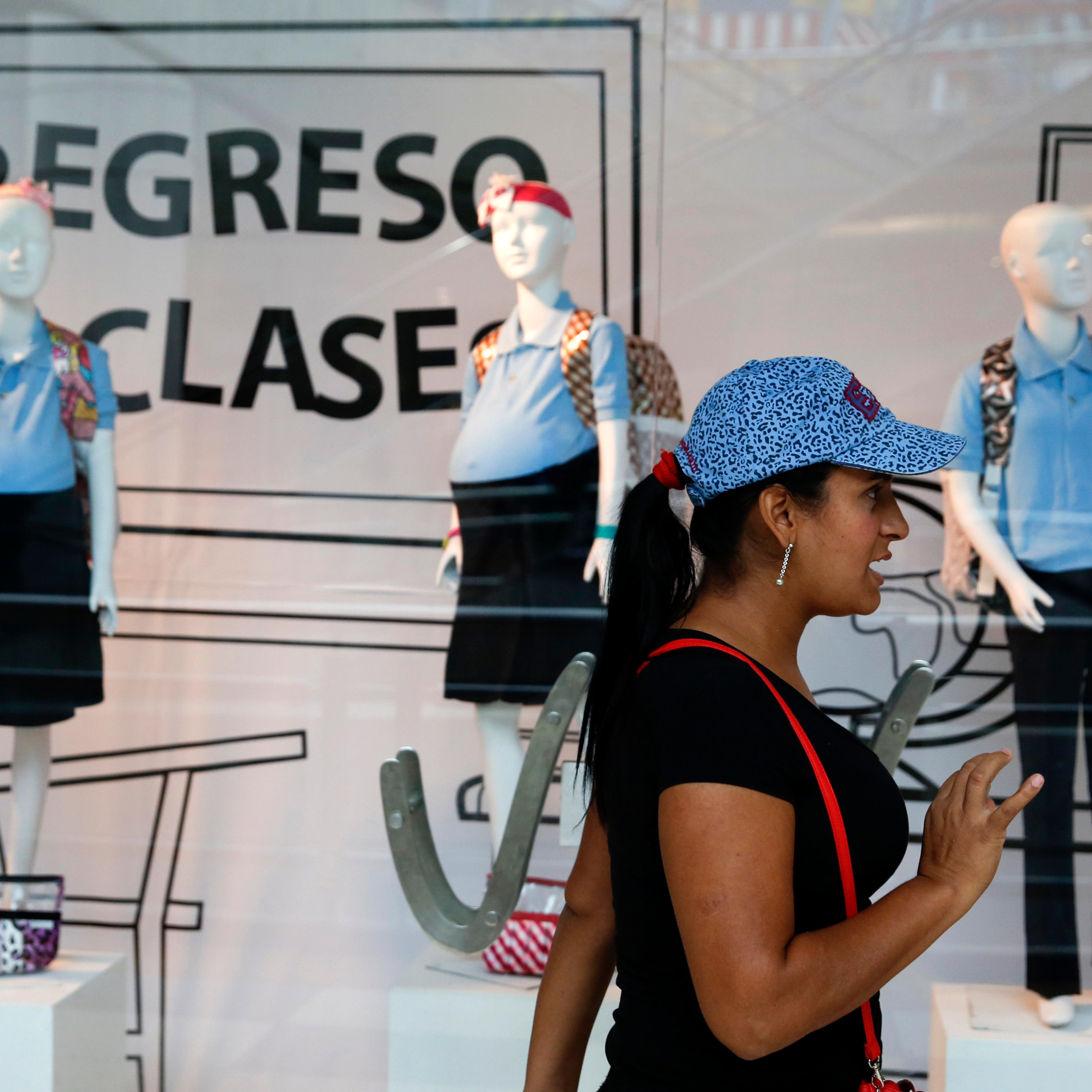 A woman reacts in front of a display showing mannequins of pregnant schoolgirls at a shopping mall in Caracas