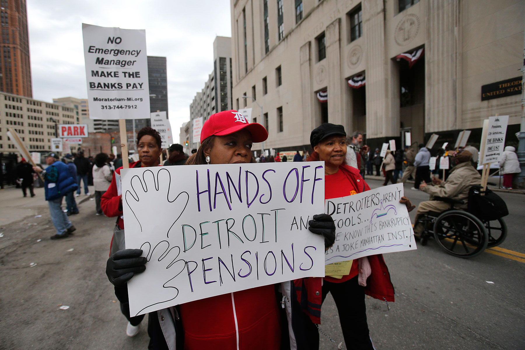 A protestor holds a sign outside the federal courthouse in support of Detroit city workers