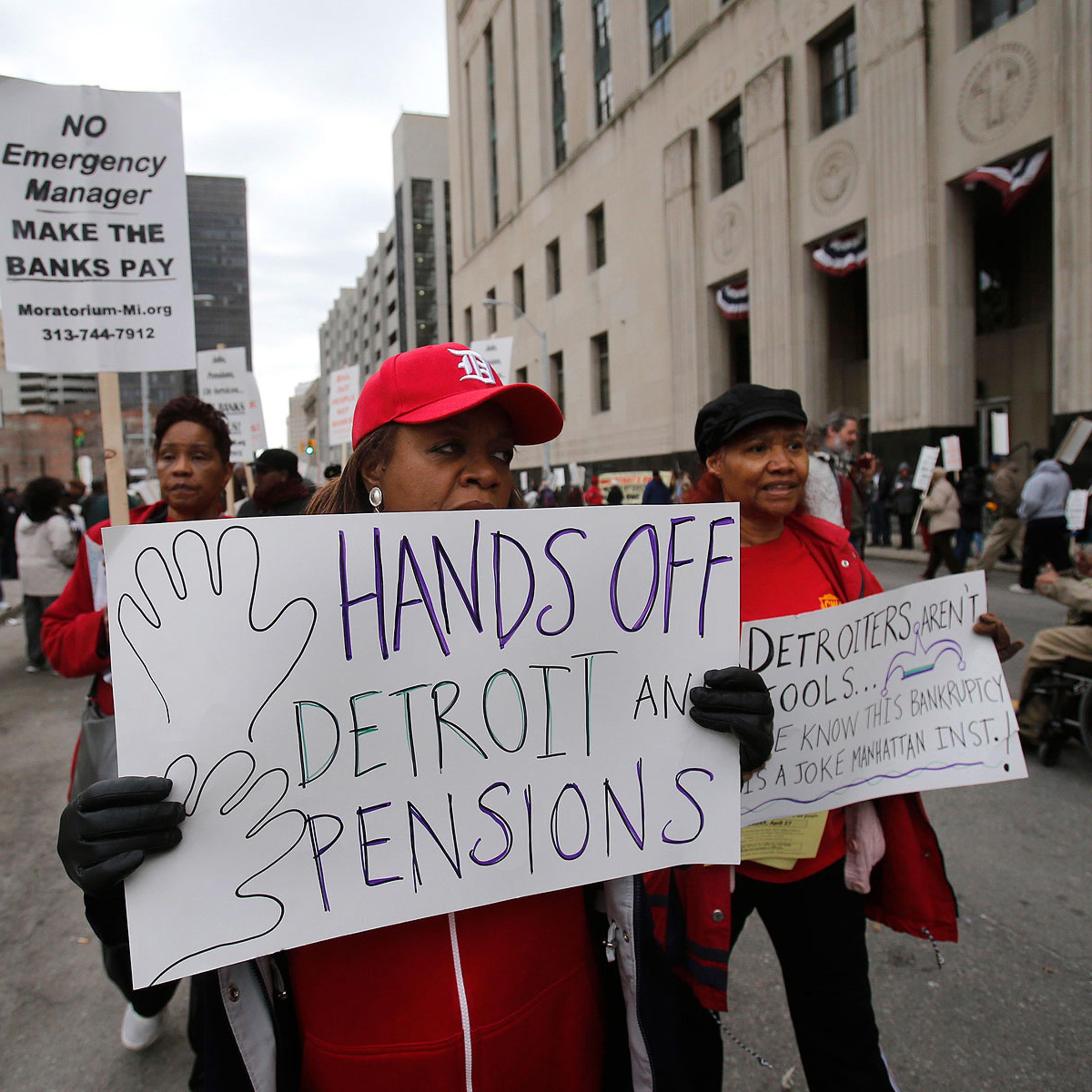 A protestor holds a sign outside the federal courthouse in support of Detroit city workers