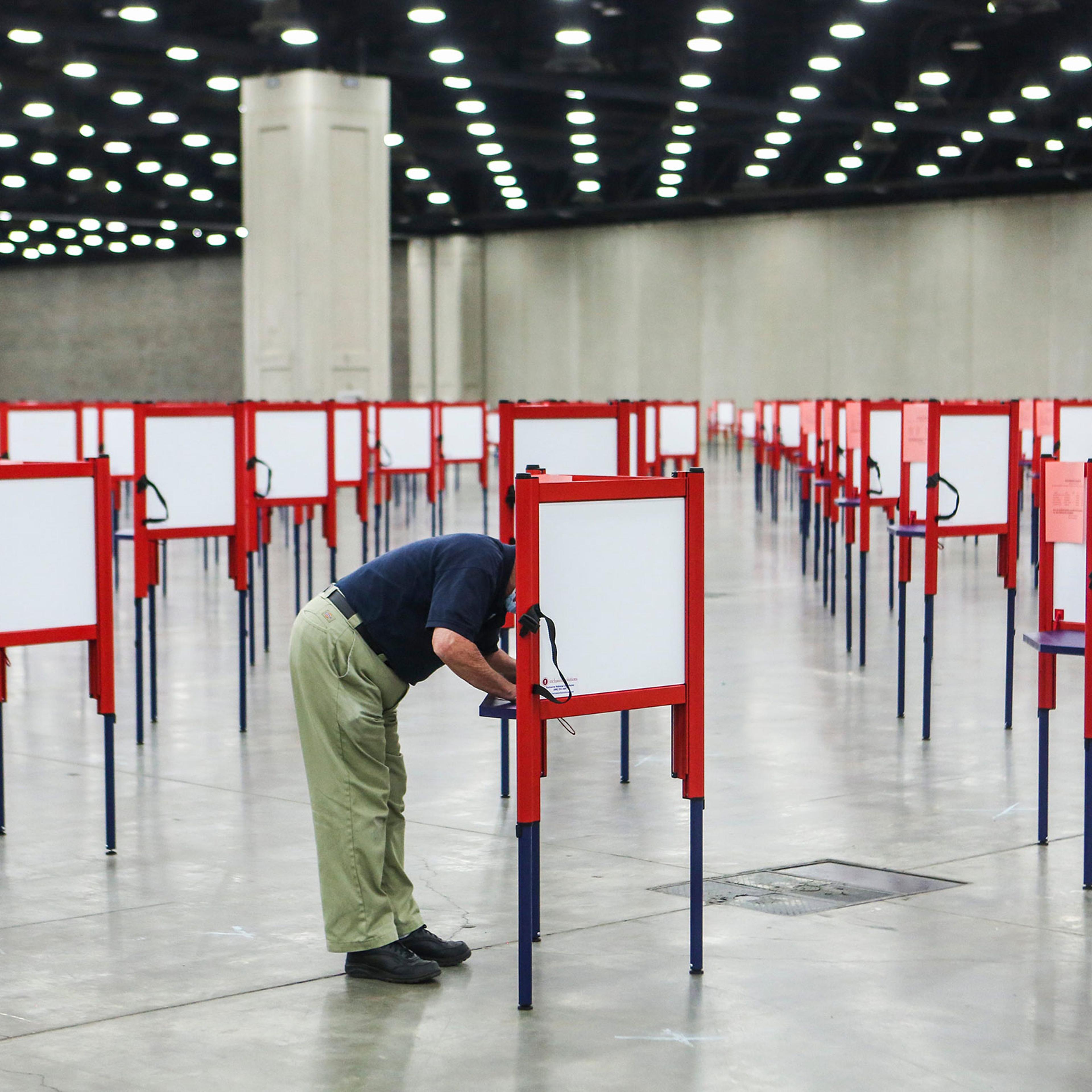 A man stands at a voting booth surrounded by many empty voting booths during early voting in Kentucky