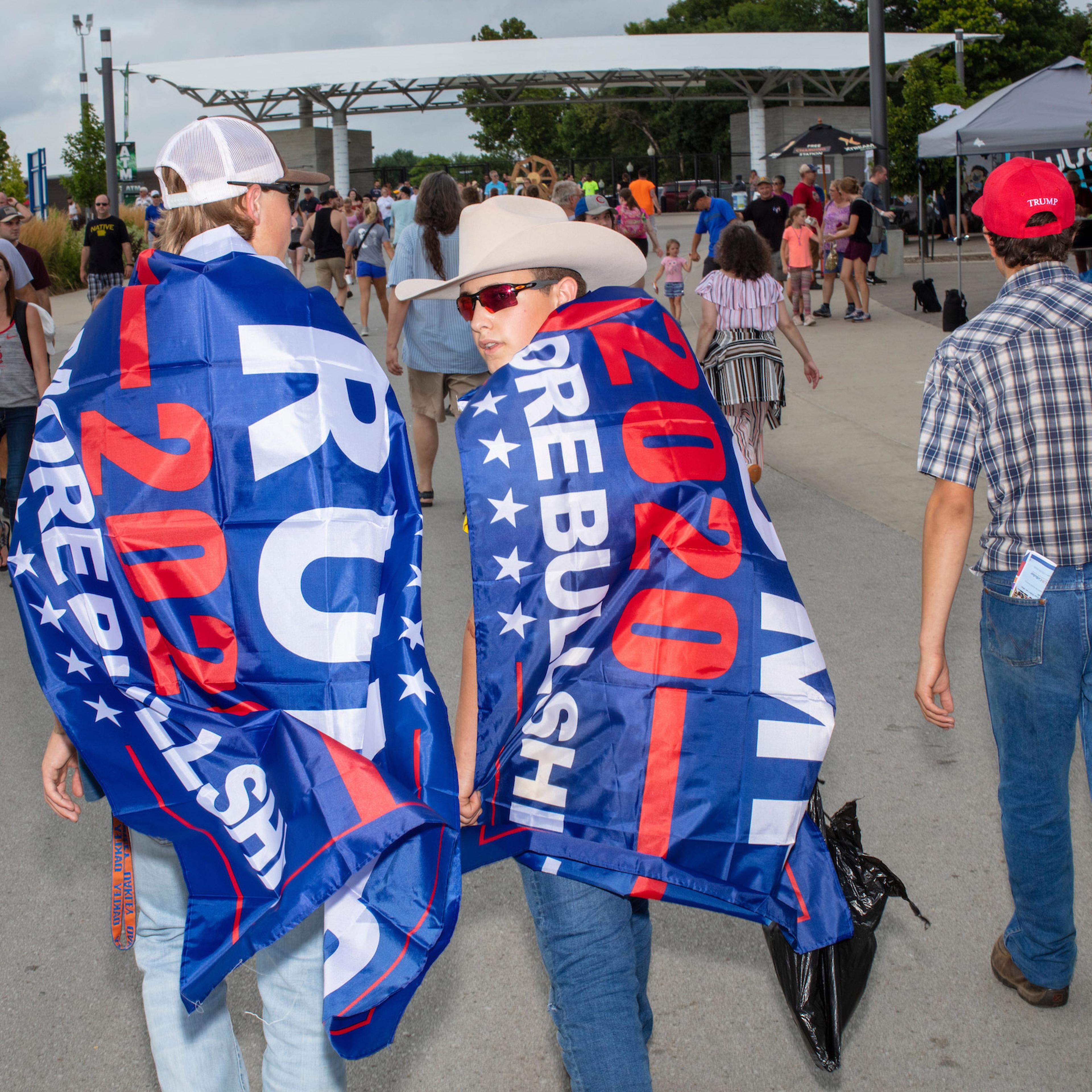 People wearing Trump flags walked ahead of the media scrum as Democratic presidential candidate Bernie Sanders walked along the midway at the Iowa State Fair in Des, Moines, Iowa, on Sun., Aug. 11, 2019.