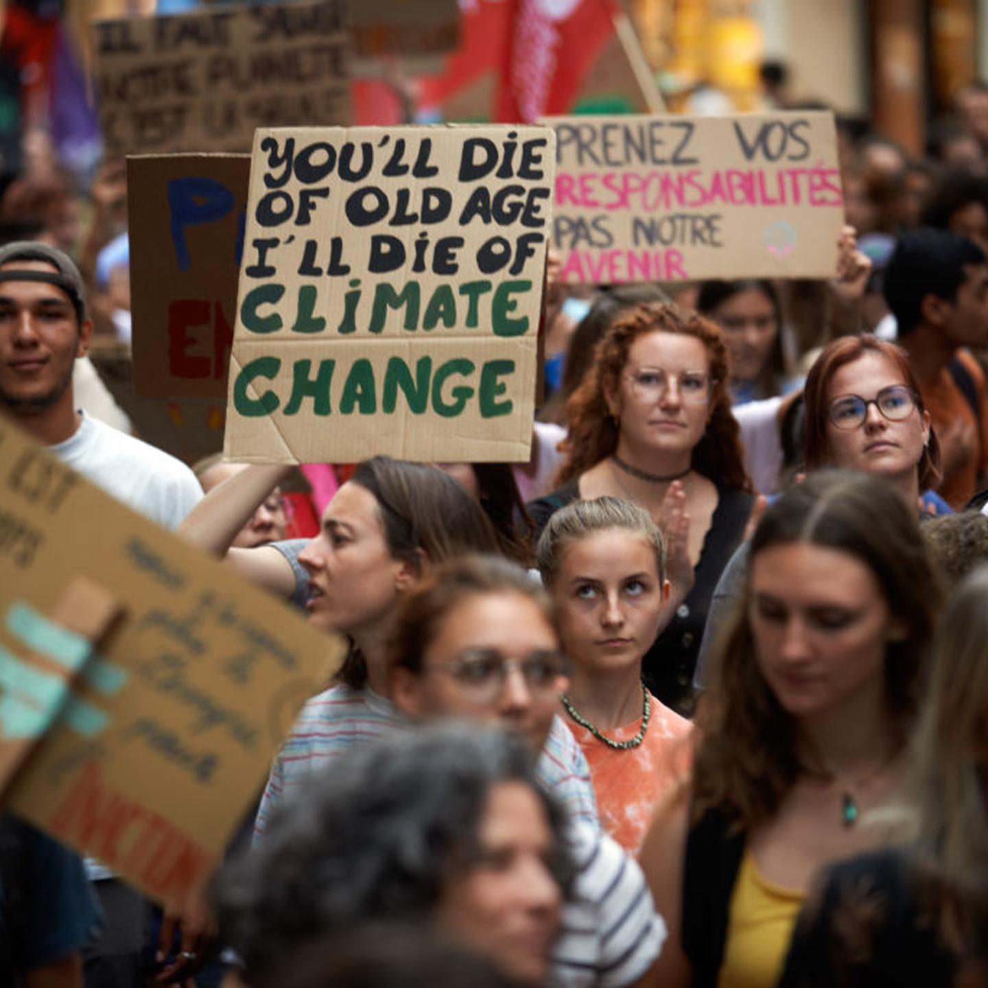 During a climate protest, a protester holds a placard reading 'You'll die of old age, I will die of climate change'.