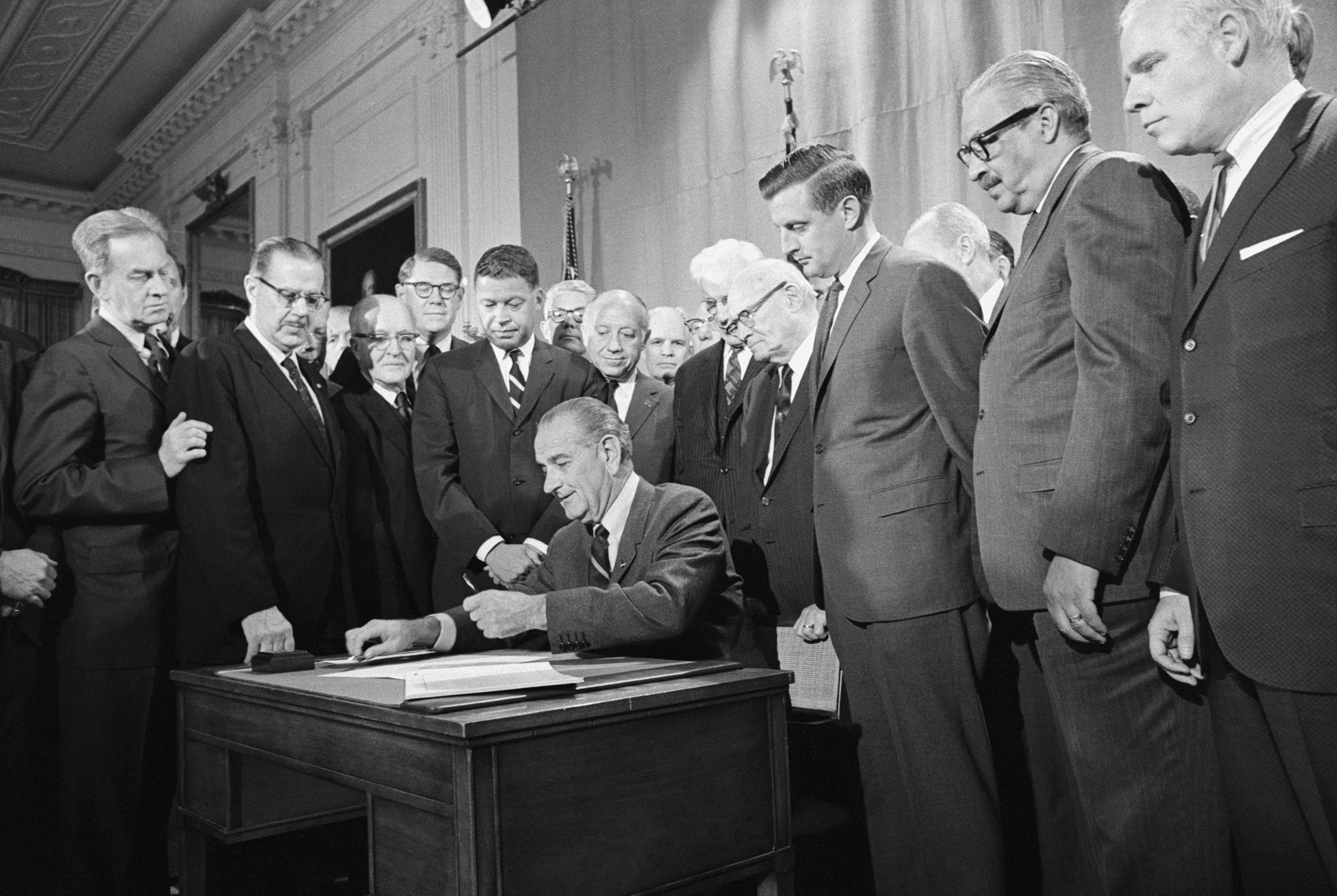 The Fair Housing Act's co-sponsors,  Democratic Senator from Minnesota Walter Mondale (third from right) and Republican Senator from Massachusetts Edward Brooke (fourth from the left in the striped tie), watch President Lyndon B. Johnson sign the civil rights bill into law on April 11, 1968.