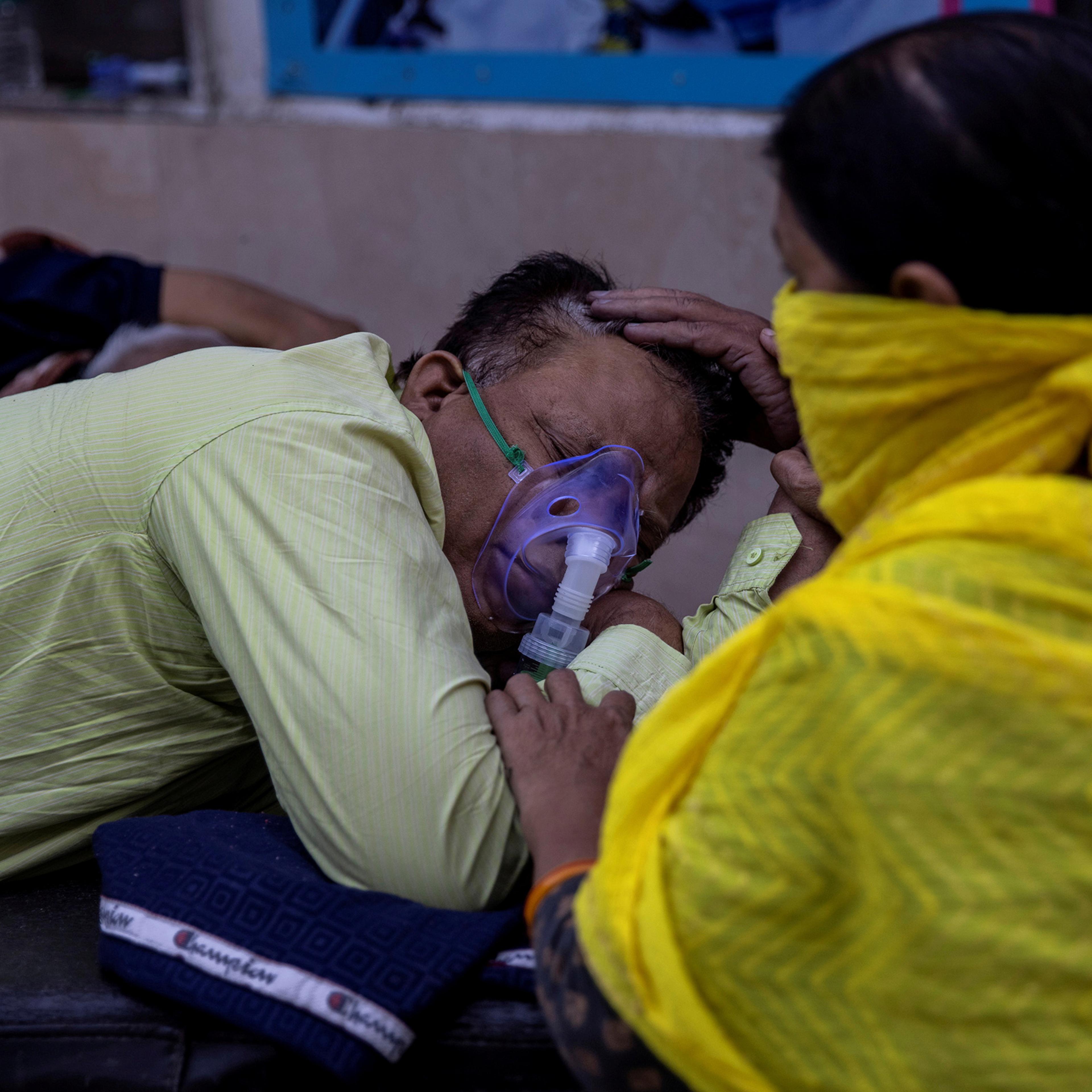 A woman takes care of her husband, who is suffering from COVID-19, as he waits to get admitted outside the casualty ward at Guru Teg Bahadur hospital in New Delhi on April 23, 2021.
