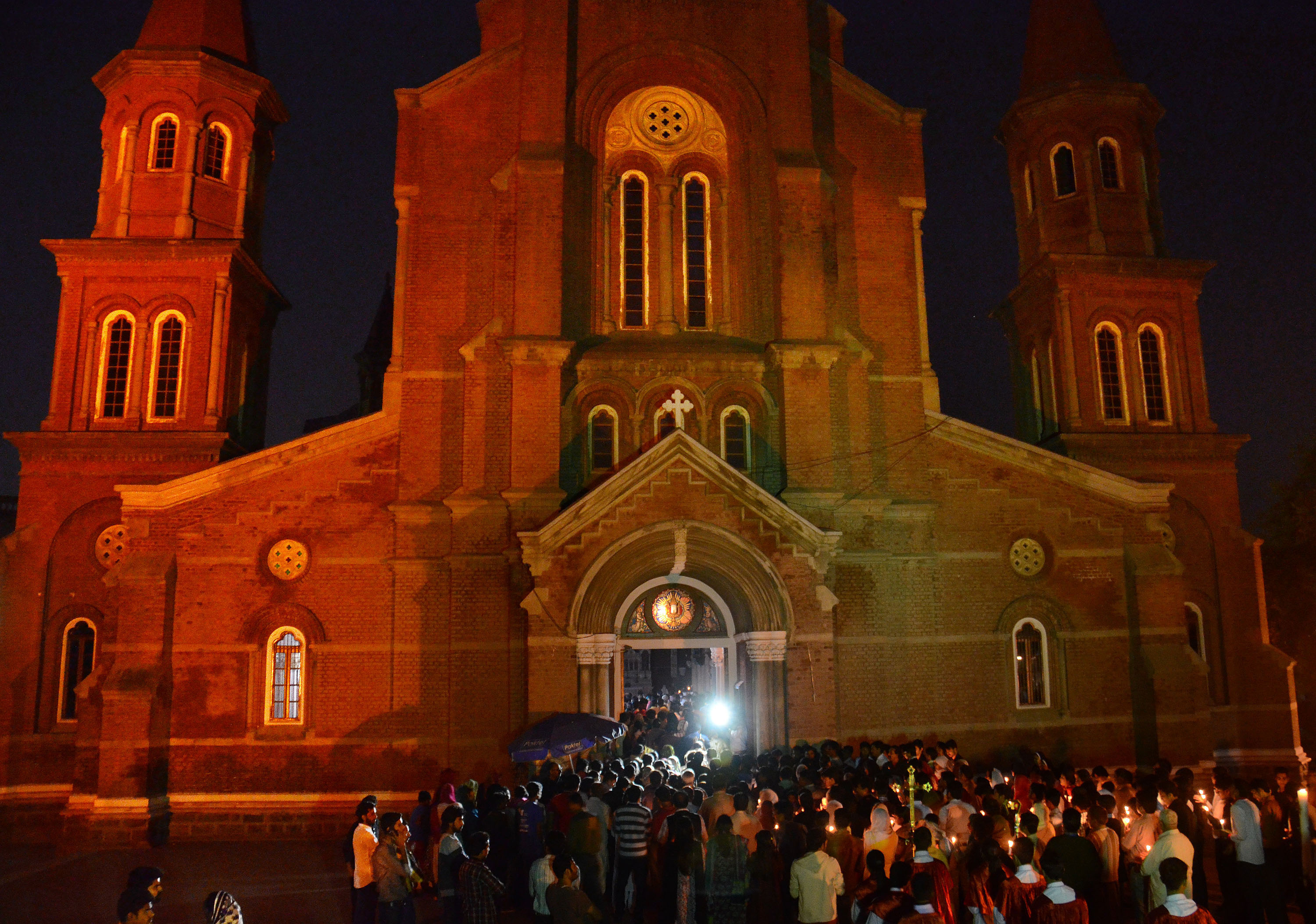 Pakistani Christian worshipers pray and hold candles during
