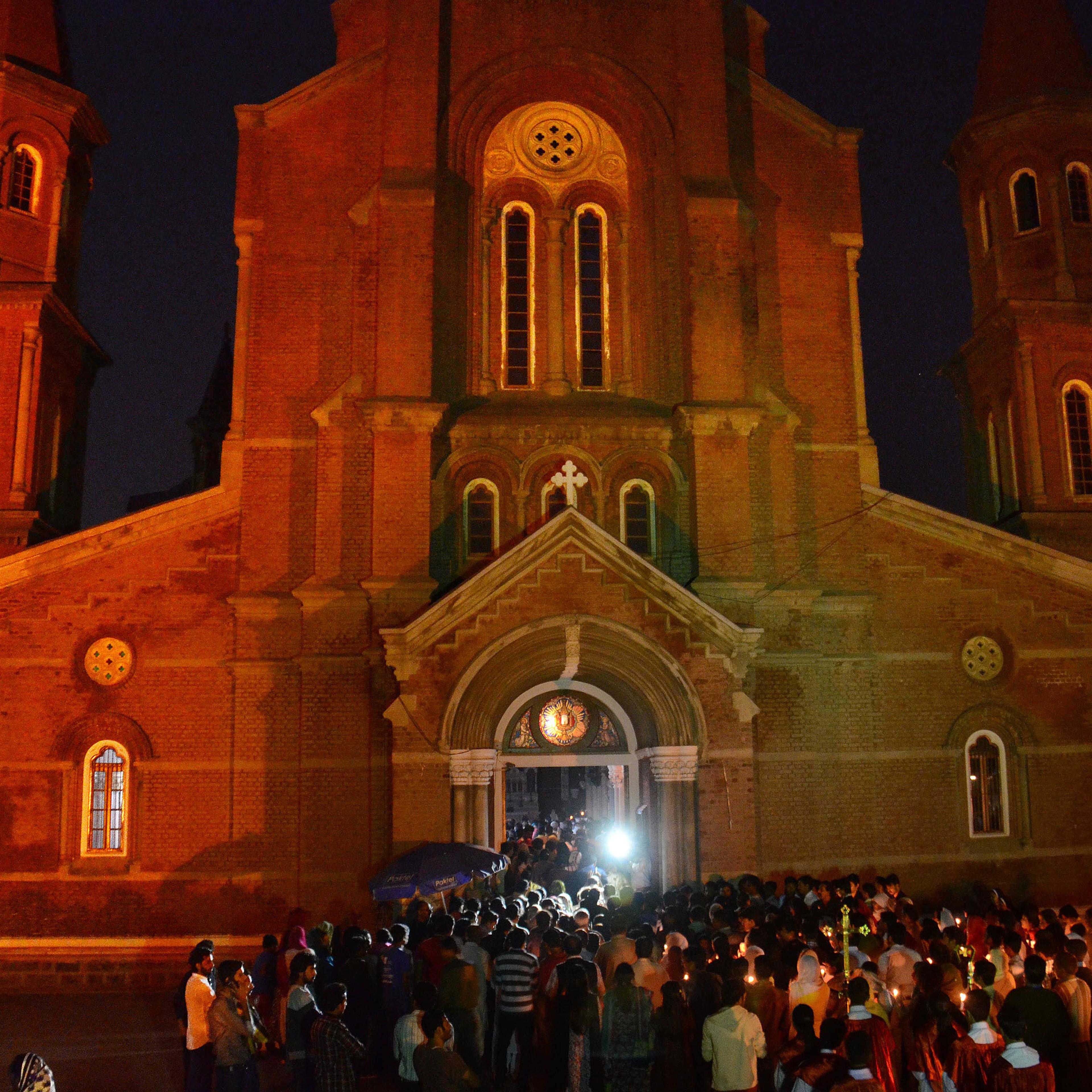 Pakistani Christian worshipers pray and hold candles during