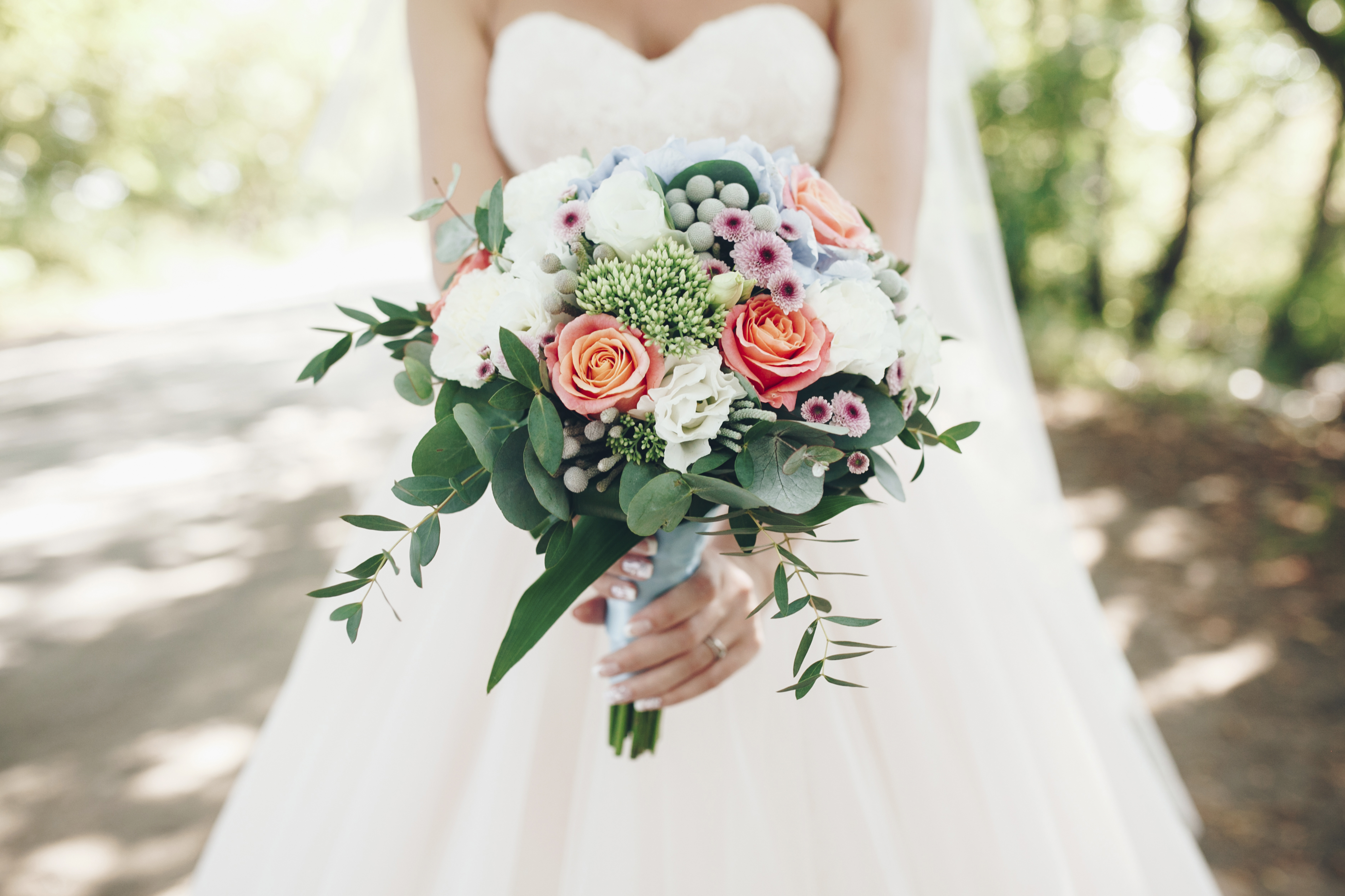 Bride holding bouquet of flowers outdoors