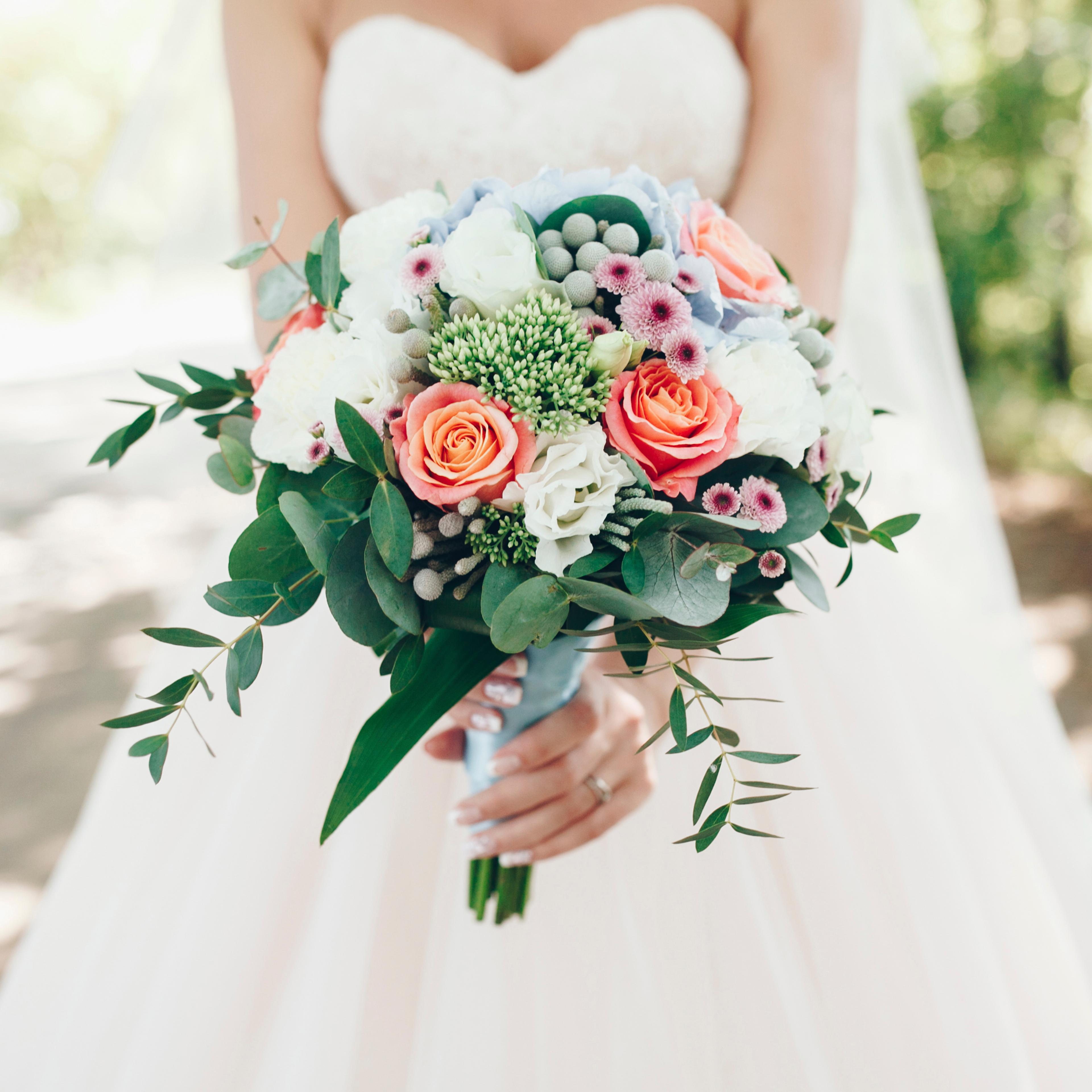 Bride holding bouquet of flowers outdoors