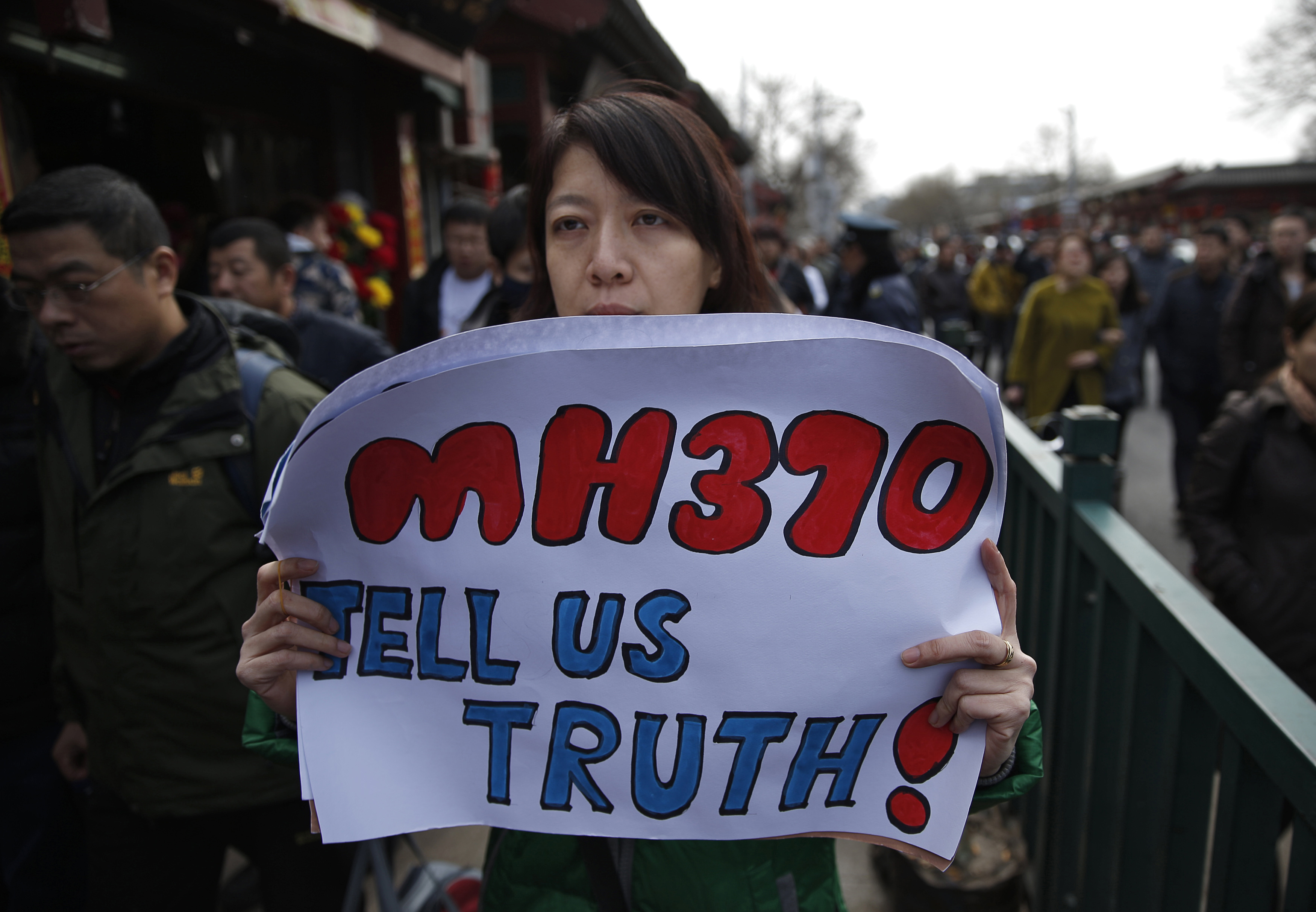 Catherine Gang, whose husband Li Zhi was onboard the missing Malaysia Airlines flight MH370, holds a banner as she walks outside Yonghegong Lama Temple after a gathering of family members of the missing passengers in Beijing