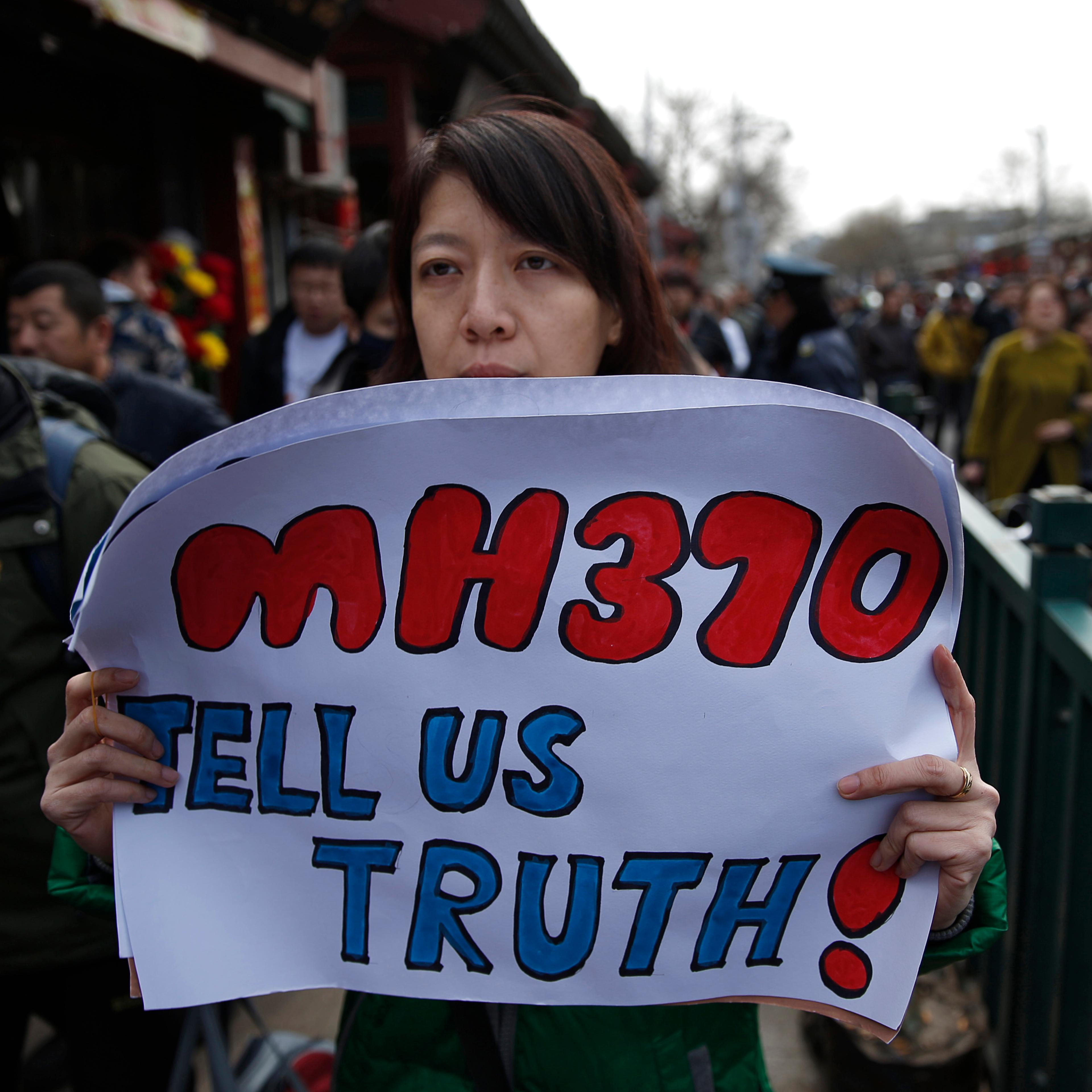 Catherine Gang, whose husband Li Zhi was onboard the missing Malaysia Airlines flight MH370, holds a banner as she walks outside Yonghegong Lama Temple after a gathering of family members of the missing passengers in Beijing