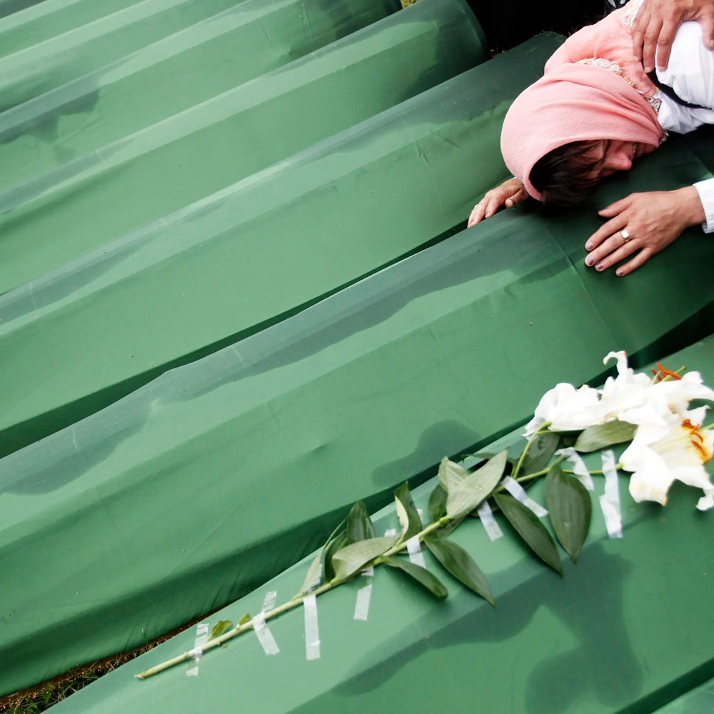A Bosnian woman cries on the coffin of a relative, which is one of the 409 coffins of newly identified victims from the 1995 Srebrenica massacre