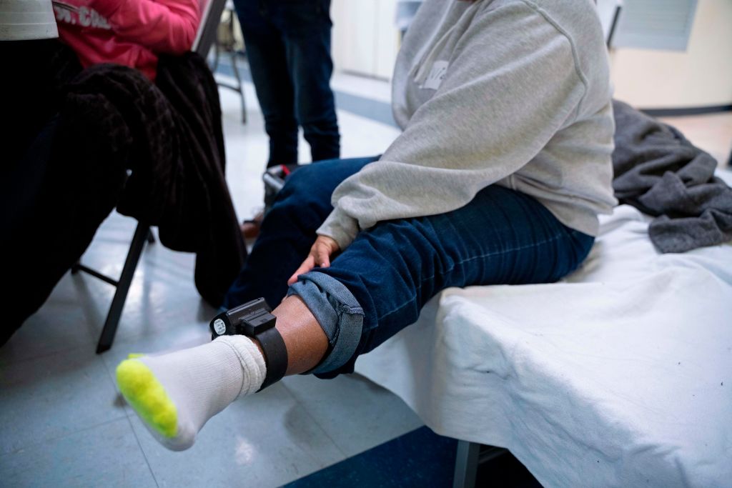 A woman from Honduras shows the ankle monitor she must wear after being released by Immigration and Customs Enforcement as she sits in the church hall of the Basilica of San Albino in Mesilla, New Mexico on Jan. 2, 2019.