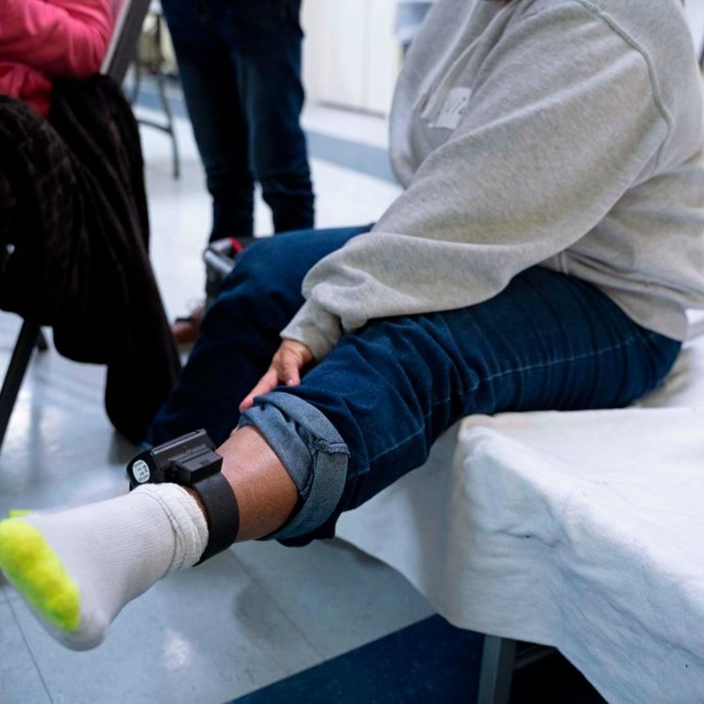 A woman from Honduras shows the ankle monitor she must wear after being released by Immigration and Customs Enforcement as she sits in the church hall of the Basilica of San Albino in Mesilla, New Mexico on Jan. 2, 2019.