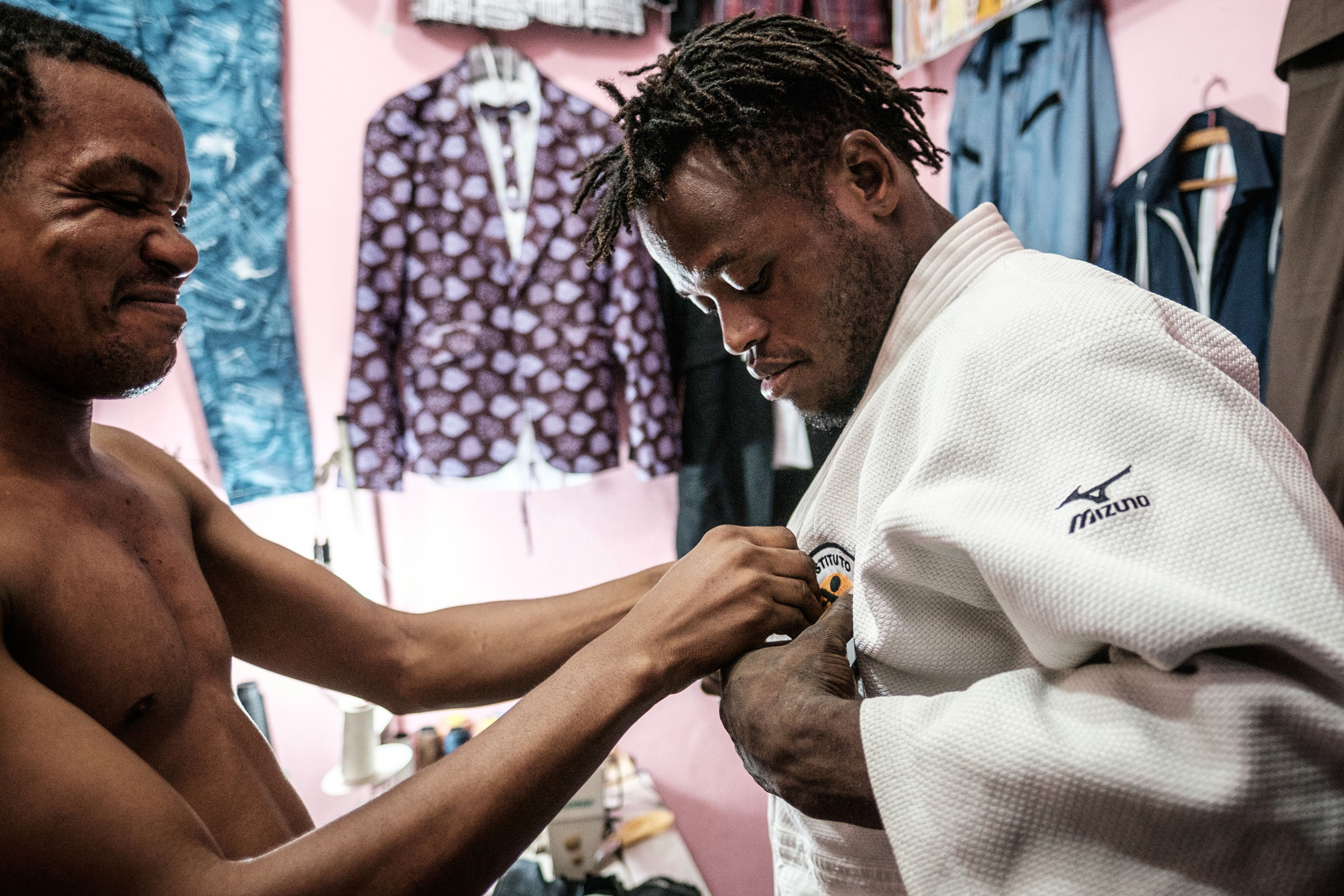 Popole Misenga a refugee judoka from the Democratic Republic of Congo, asks a friend to stitch a sponsor'ss badge on his judogi in Rio de Janeiro on April 14, 2016.