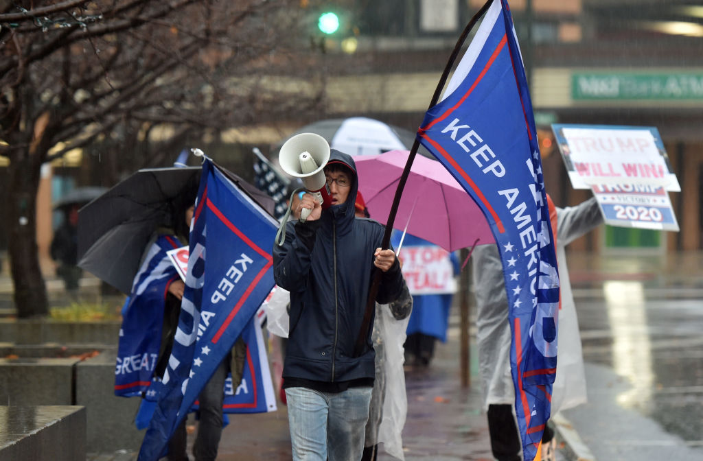 A protester holding a flag chants slogans on a megaphone