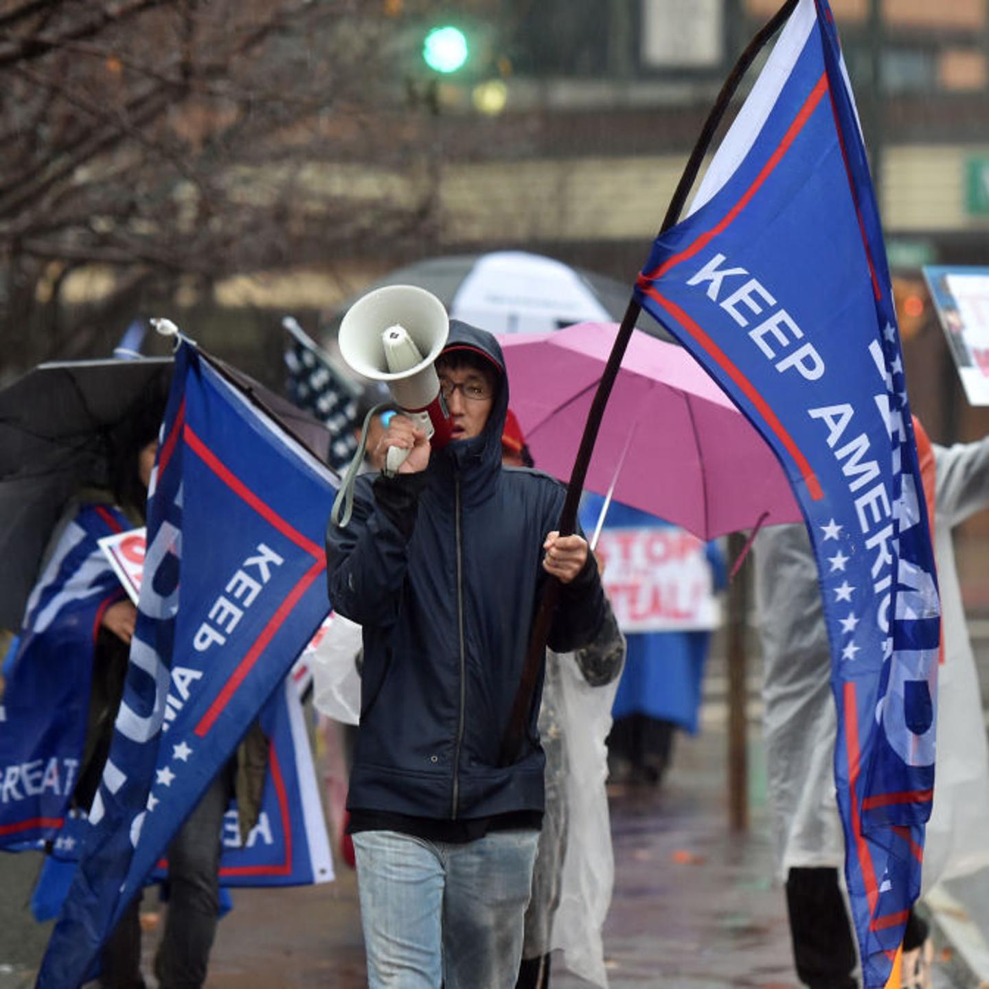 A protester holding a flag chants slogans on a megaphone