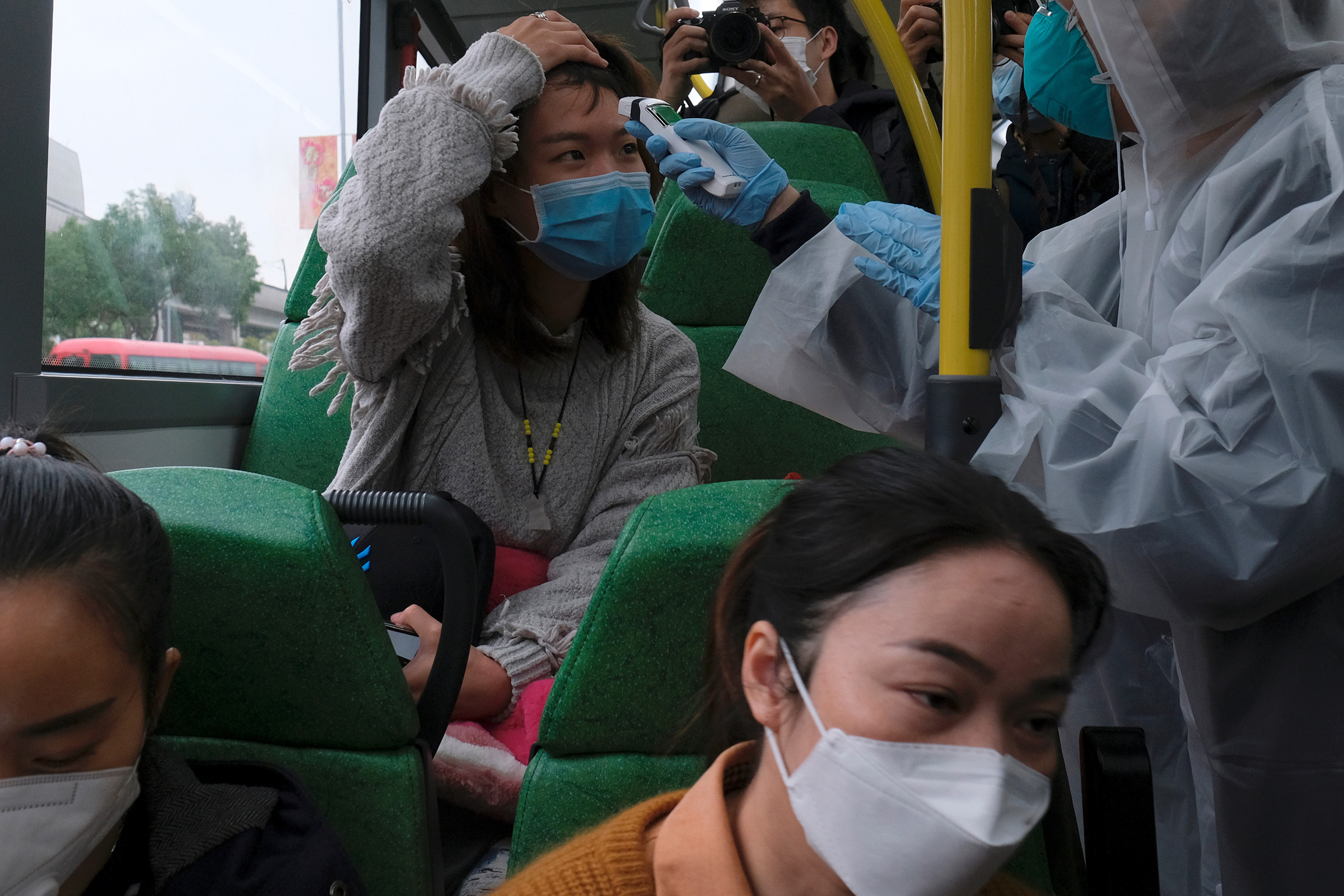 A resident volunteers to take the temperature of a passenger following the outbreak of a new coronavirus at a bus stop at Tin Shui Wai, a border town in Hong Kong, China, Feb. 4, 2020.