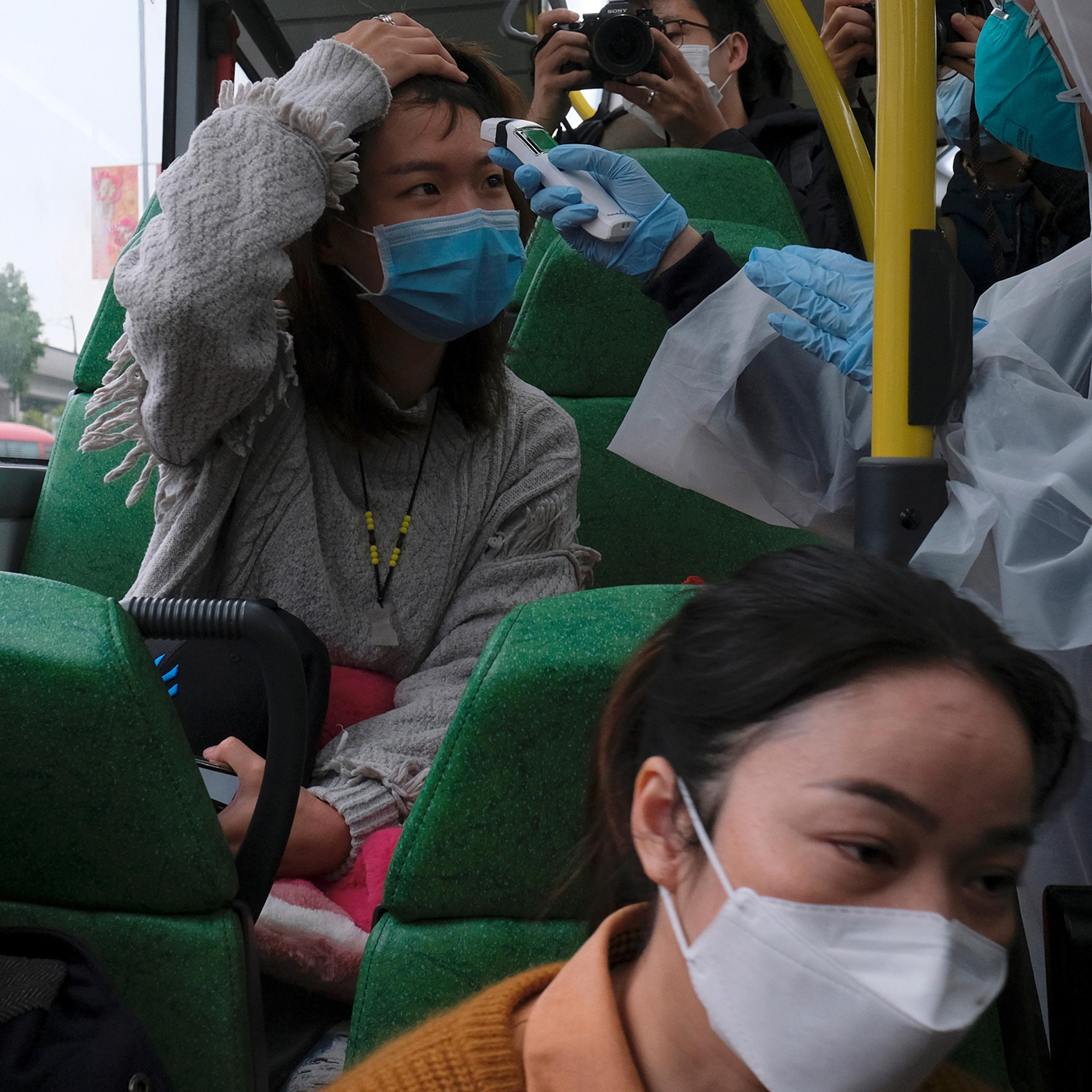 A resident volunteers to take the temperature of a passenger following the outbreak of a new coronavirus at a bus stop at Tin Shui Wai, a border town in Hong Kong, China, Feb. 4, 2020.