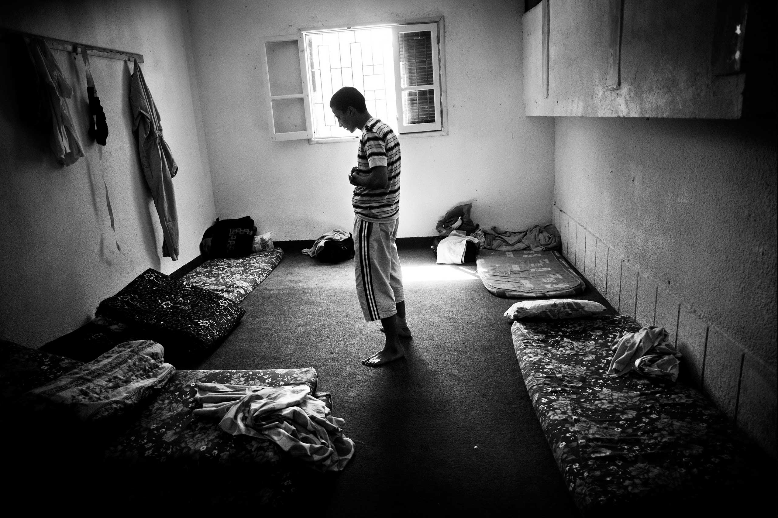 Suspected of being a Gaddafi loyalist prays at her cage in a school run by militias as a temporary prison in Misratah, Libya, Sep. 2011.