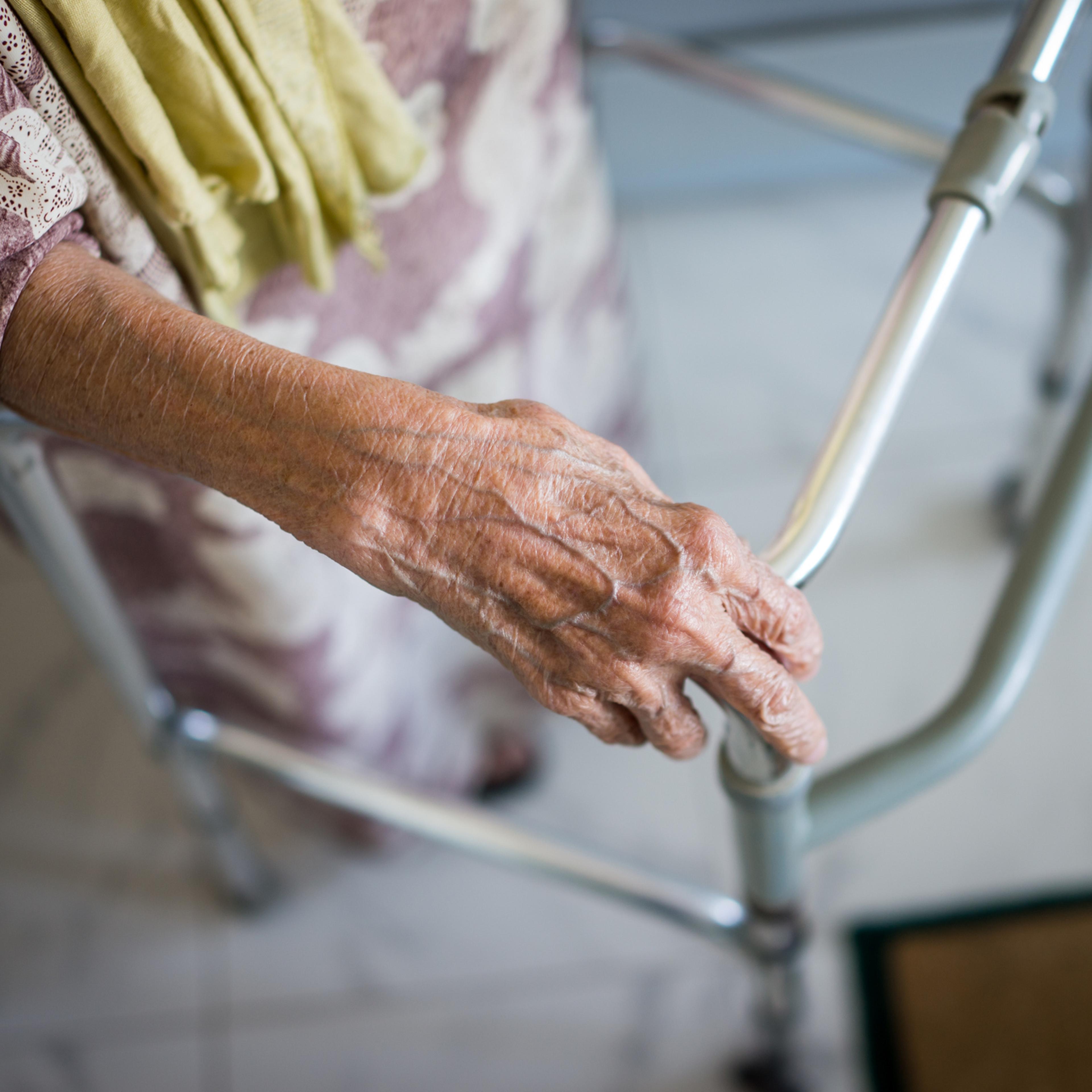 An old woman uses a walker