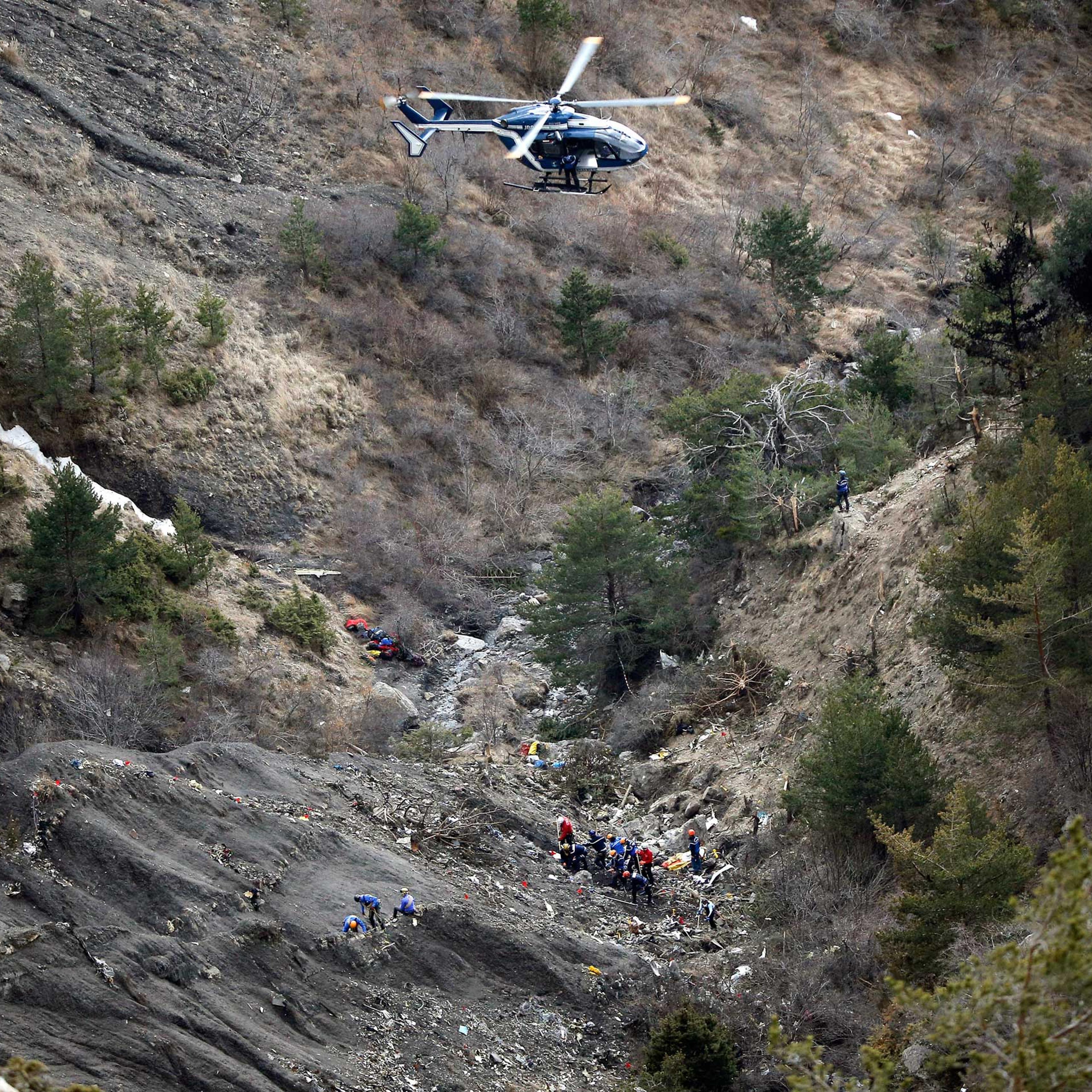 A helicopter flies overhead as rescue workers work at the crash site of Germanwings passenger plane near Seyne-les-Alpes, France, on March 26, 2015.
