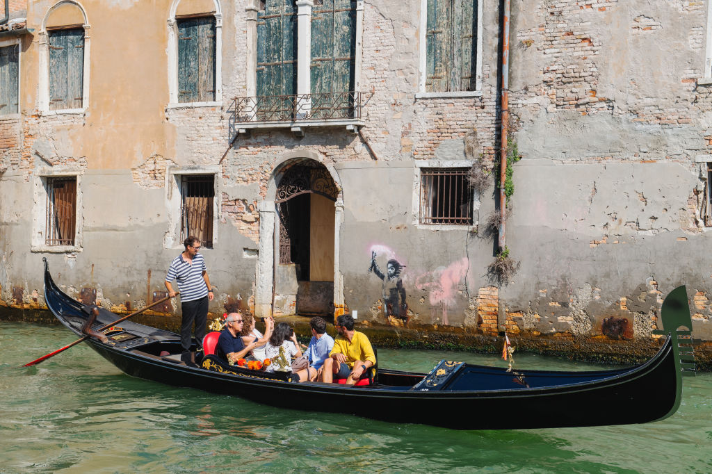 A view of street artist Banksy's work of a migrant child appears on the outer wall of a house overlooking the Rio Ca Fossari, made by the artist during the 58th International Art Biennale on May 15, 2019 in Venice.
