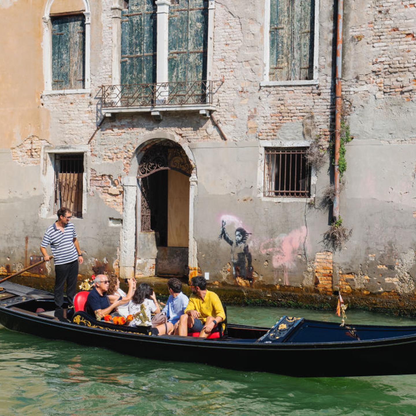 A view of street artist Banksy's work of a migrant child appears on the outer wall of a house overlooking the Rio Ca Fossari, made by the artist during the 58th International Art Biennale on May 15, 2019 in Venice.