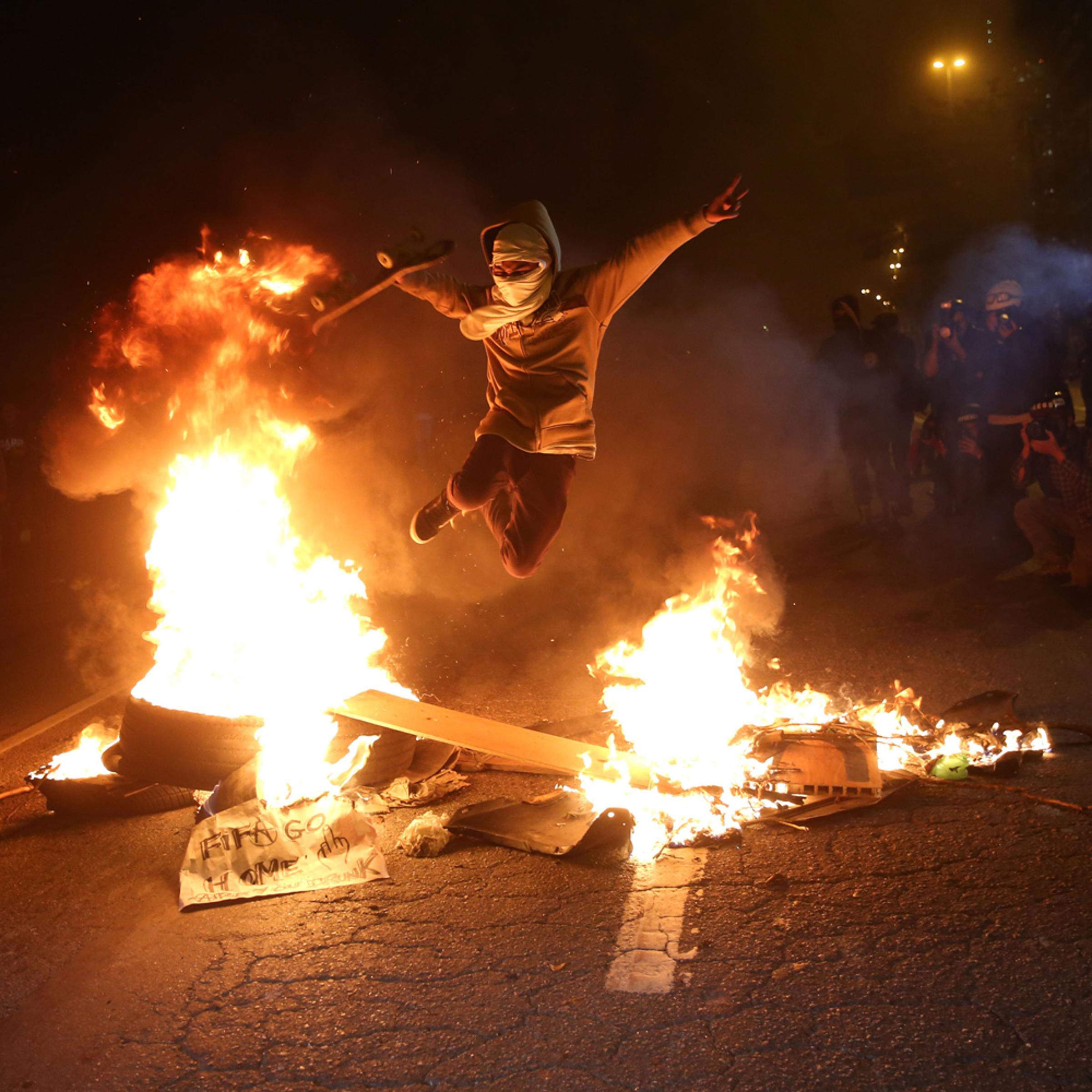 A protester jumps over a fire barricade during a protest against 2014 FIFA World Cup in Sao Paulo, on June 19, 2014.