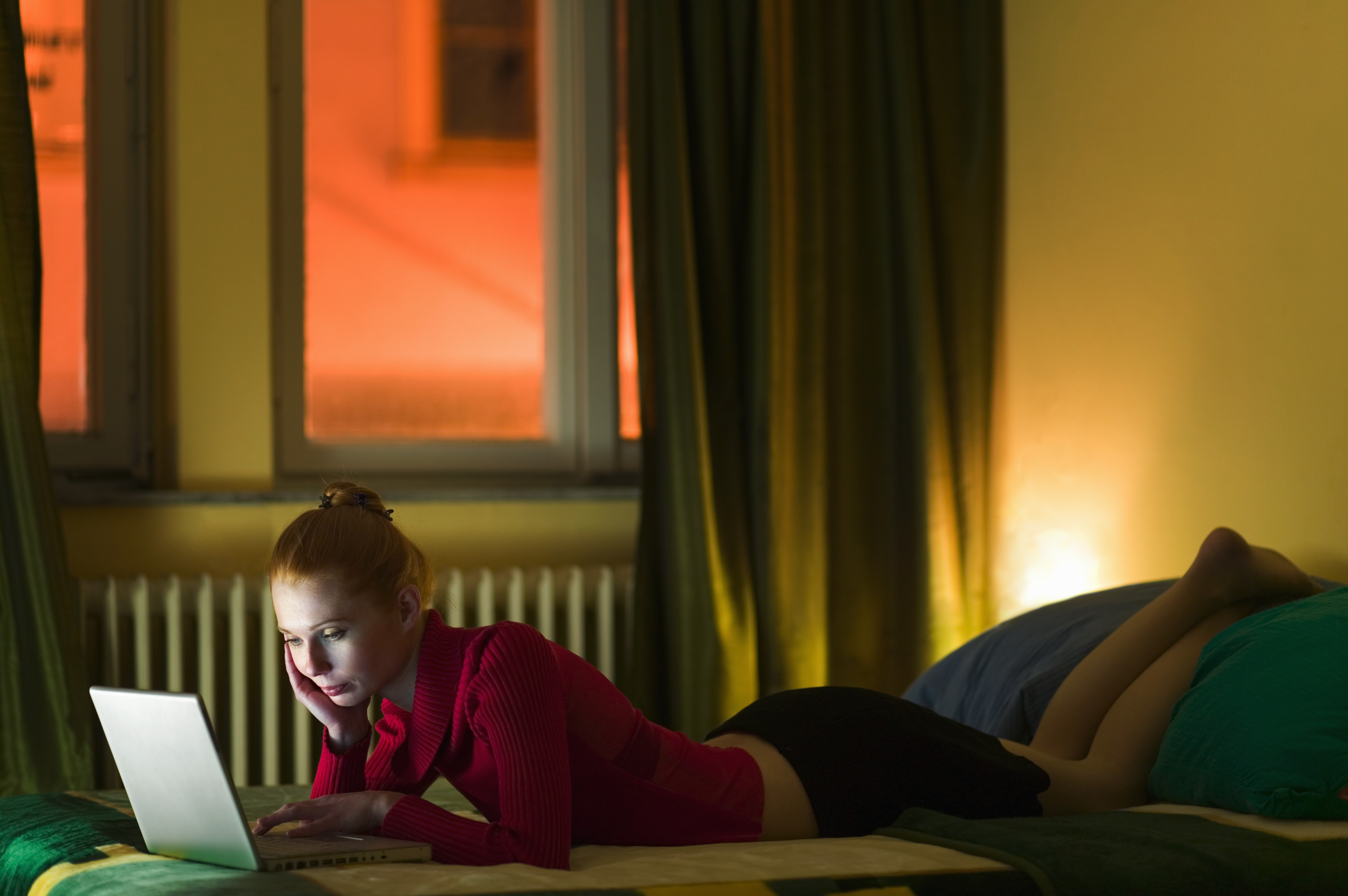 Young woman using laptop on bed