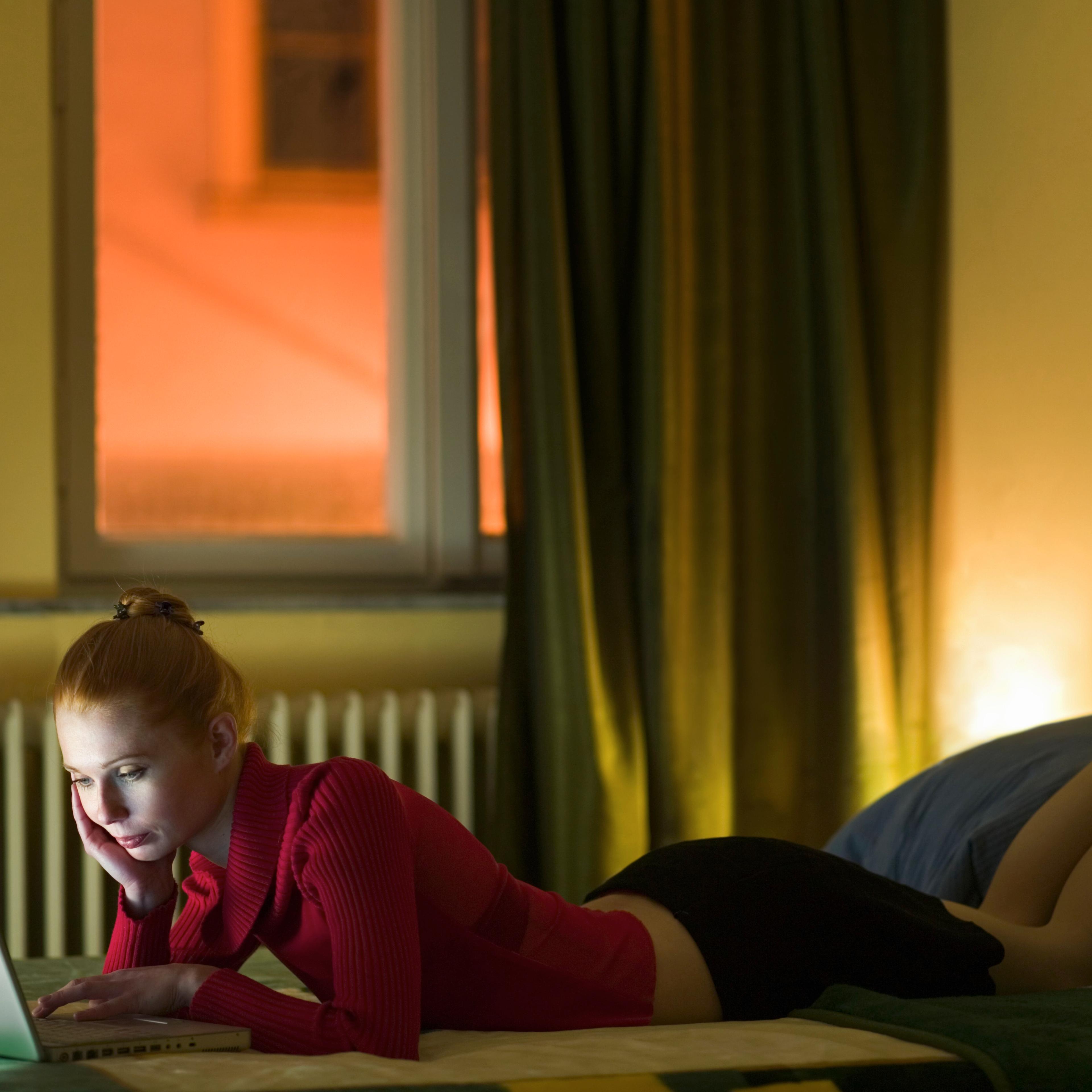 Young woman using laptop on bed